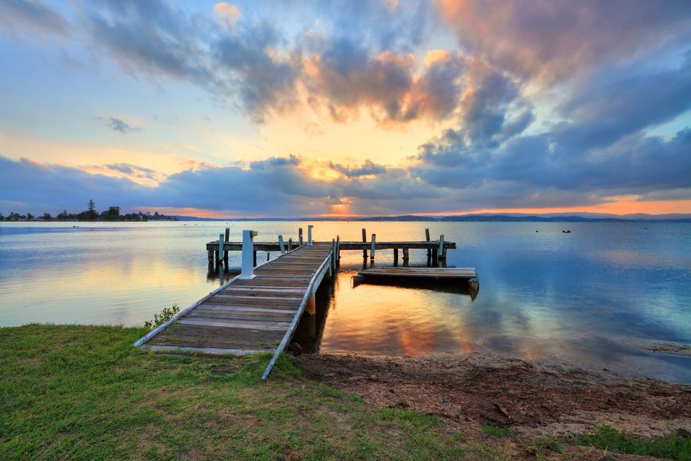 There is a Dock in the Middle of a Lake at Sunset — Trade & General Towing in Belmont, NSW