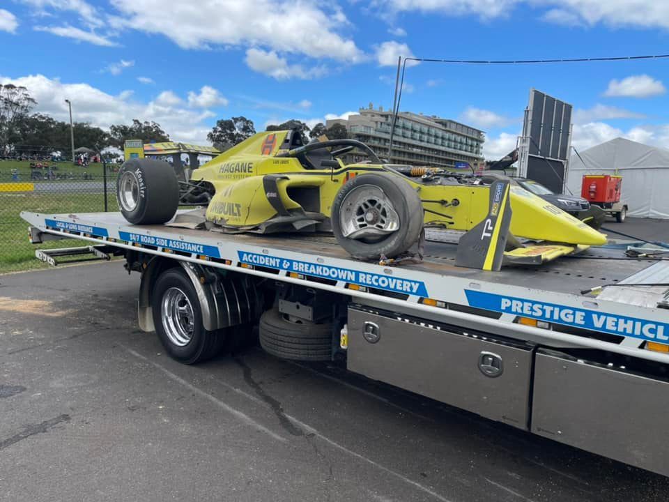 Yellow race car loaded on a tow truck.