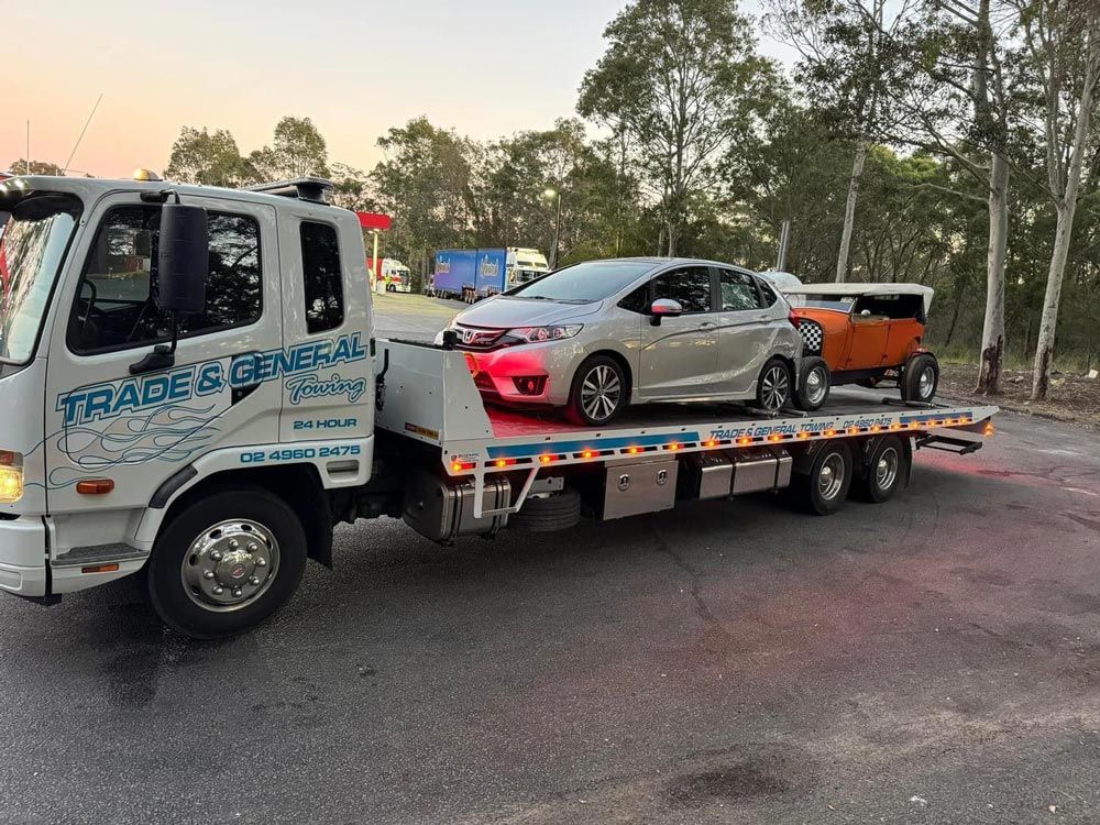 White Truck Towing Two Different Vehicles on the Roadside — Trade & General Towing in Sandgate, NSW