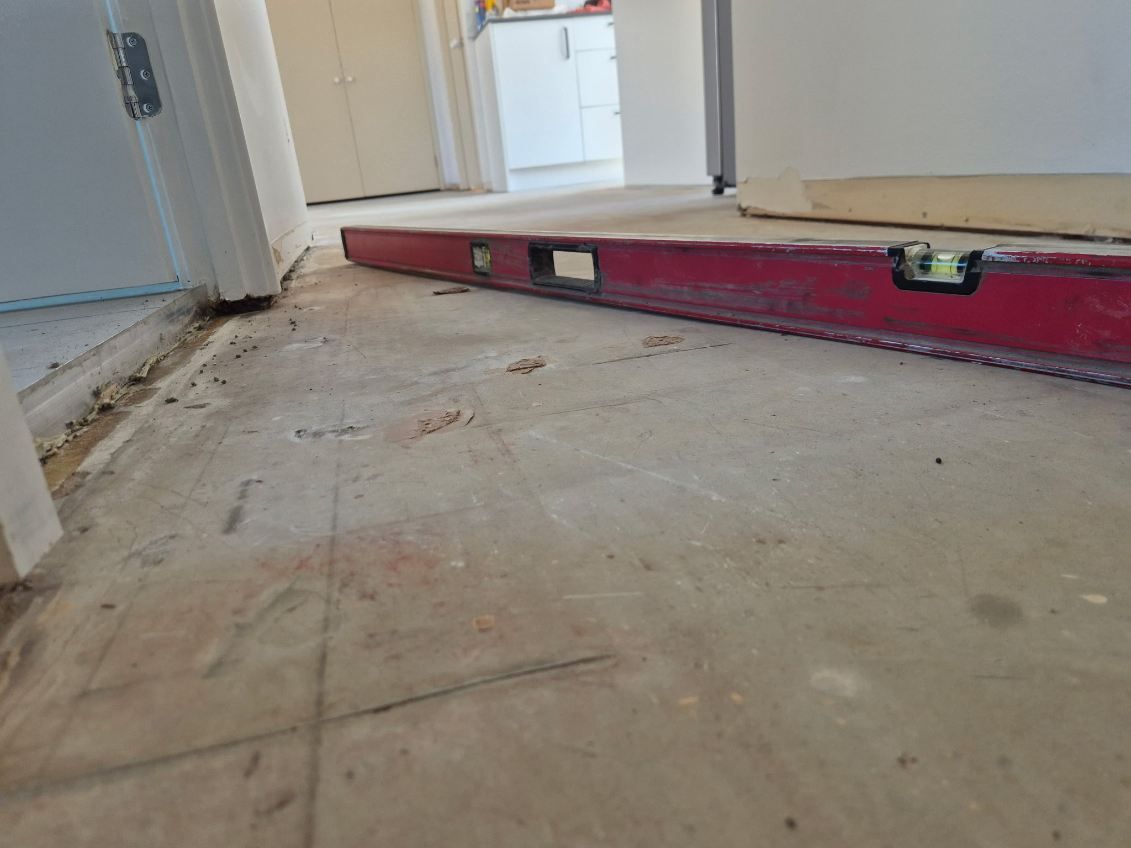 Interior floor with a red level tool and unfinished flooring in a hallway