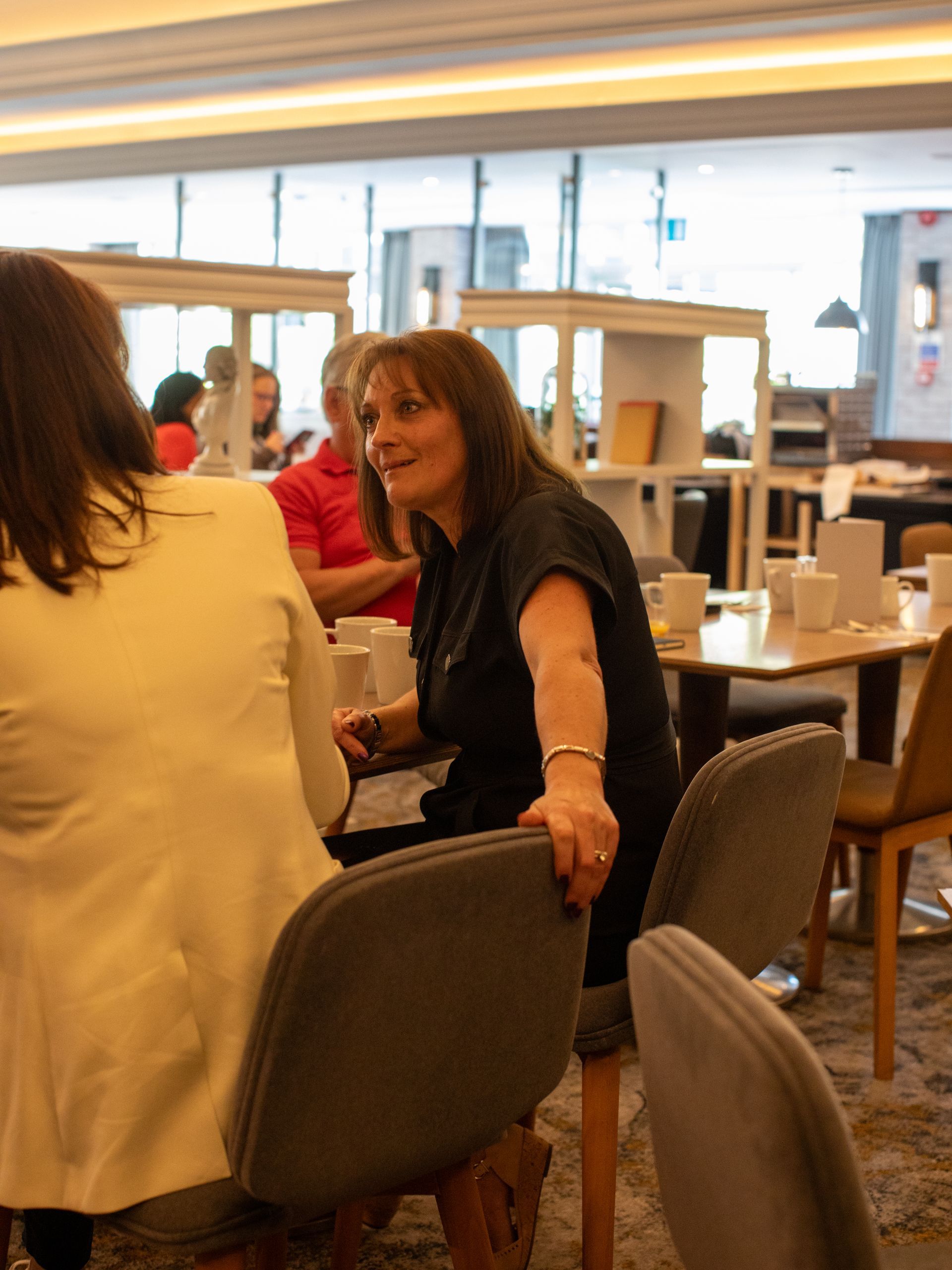 A woman in a black shirt is sitting at a table in a restaurant