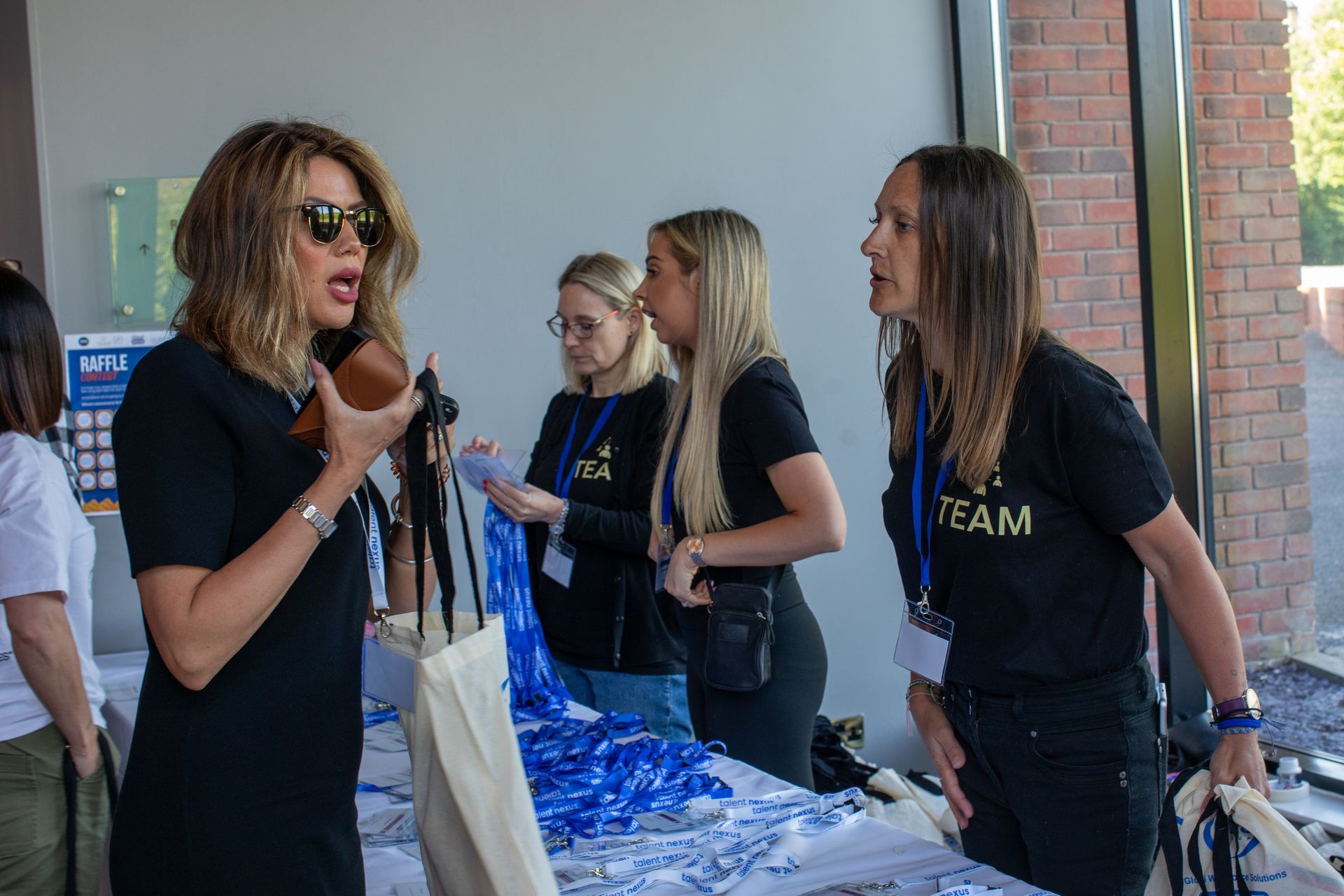 A group of women are standing around a table talking to each other.
