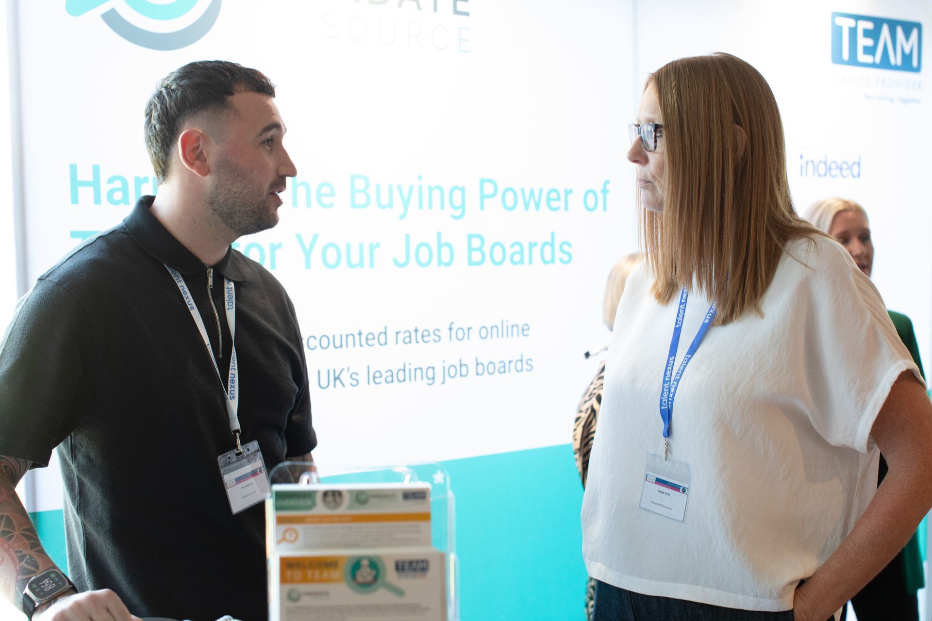 A man and a woman are talking to each other at a job fair.