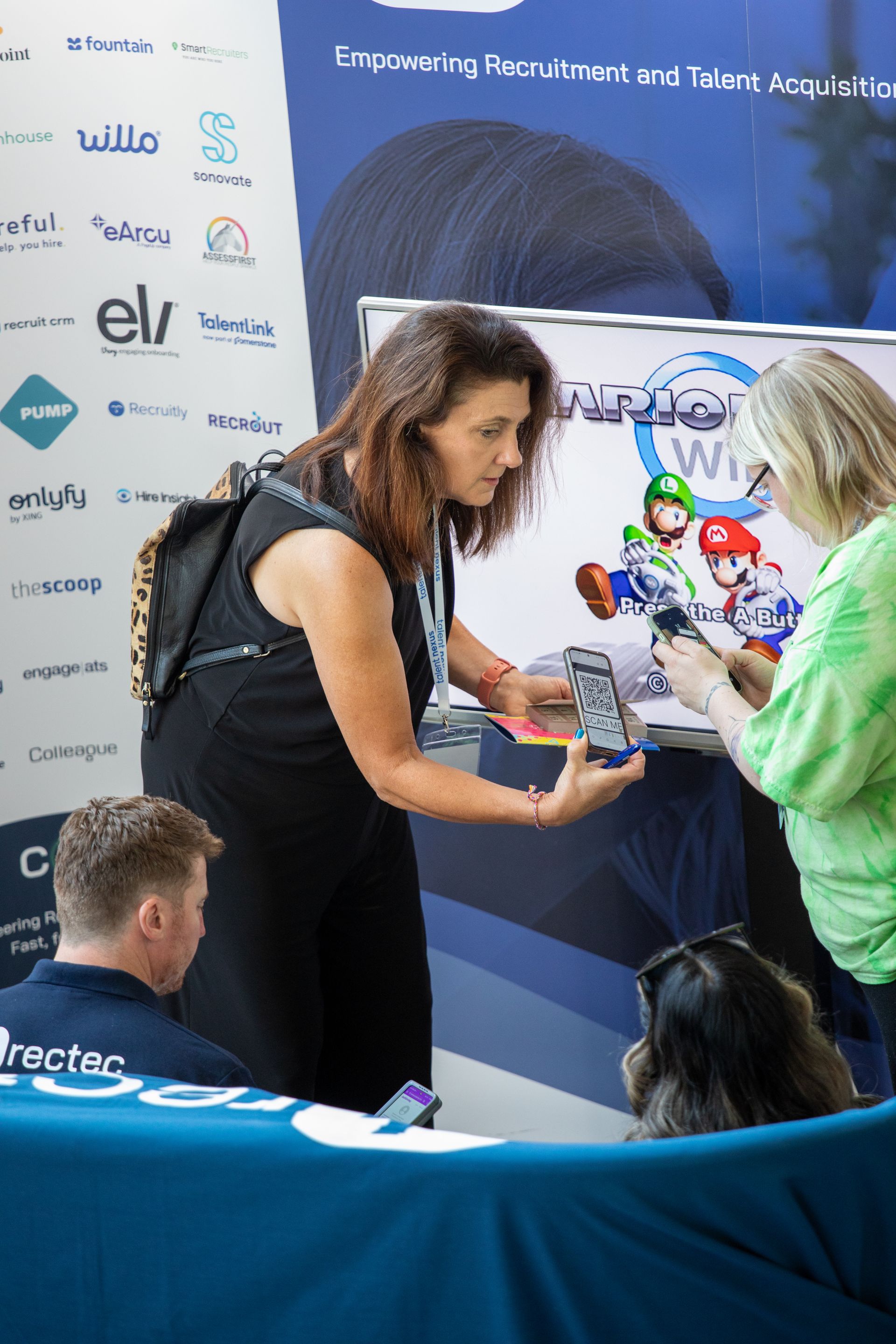 A woman is holding a cell phone in front of a group of people.