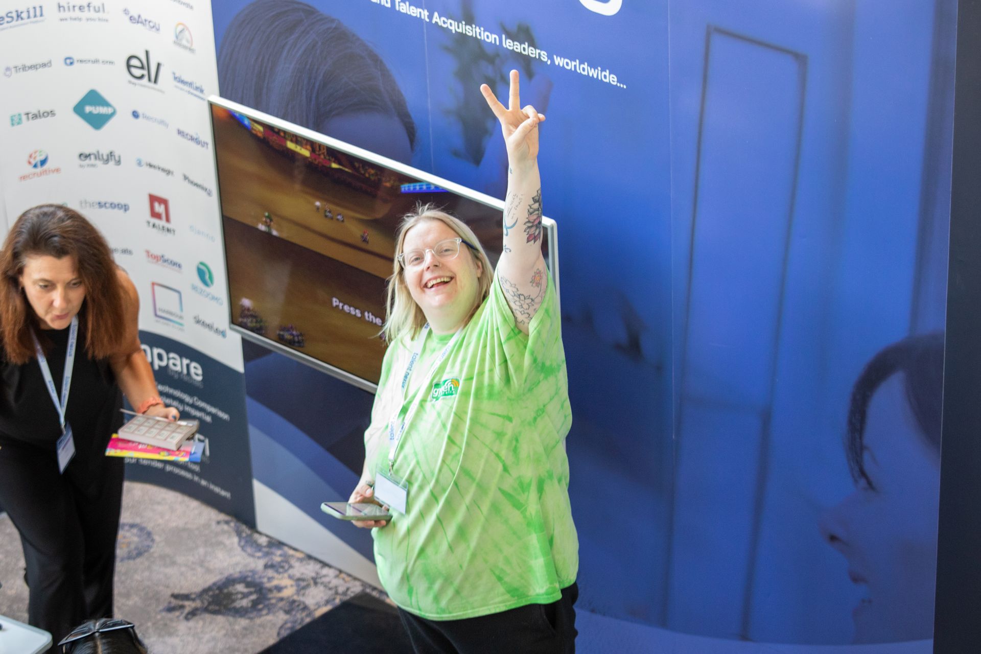 A woman in a green shirt is giving a peace sign