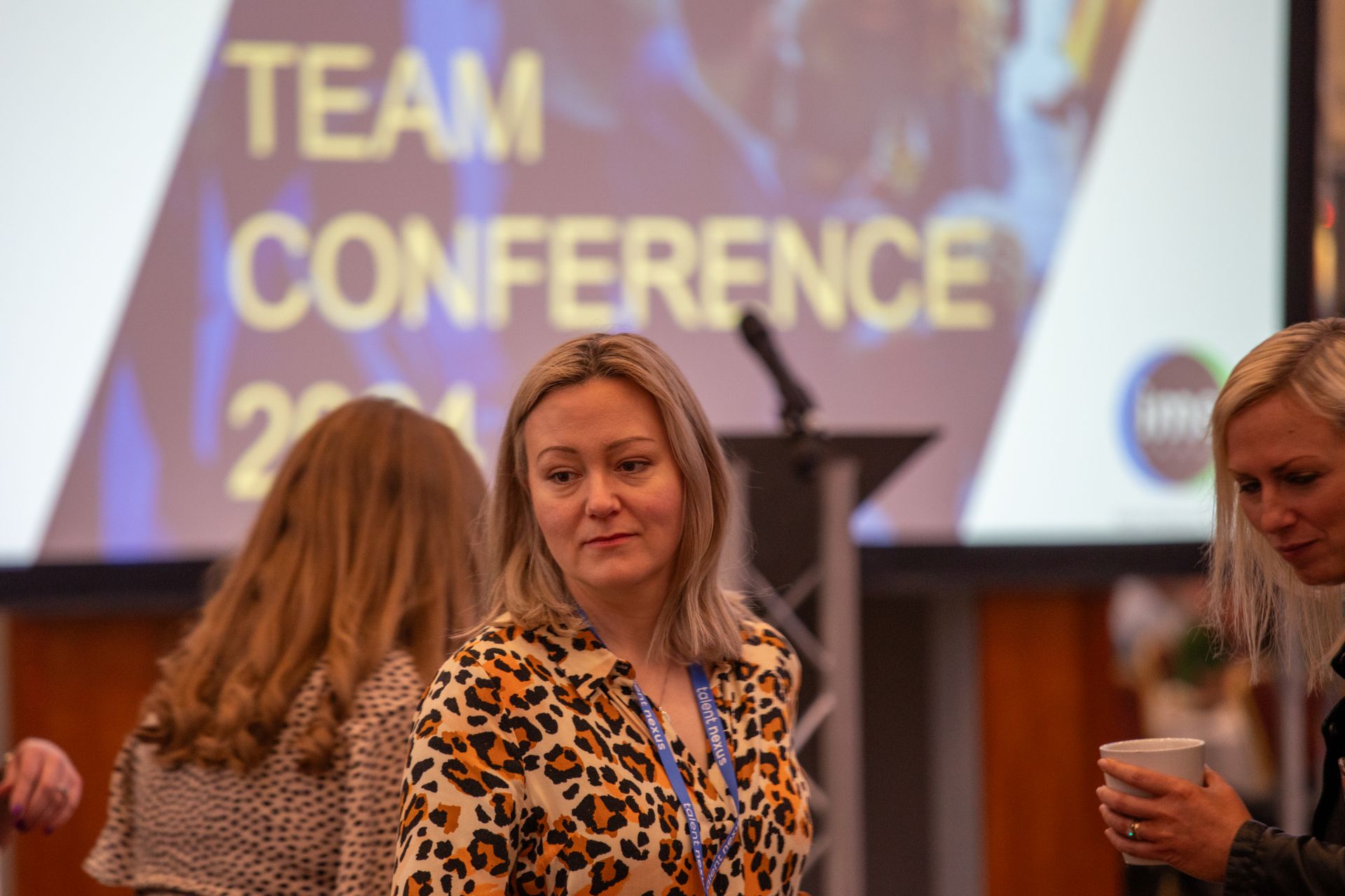 A group of women are standing in front of a sign that says team conference.