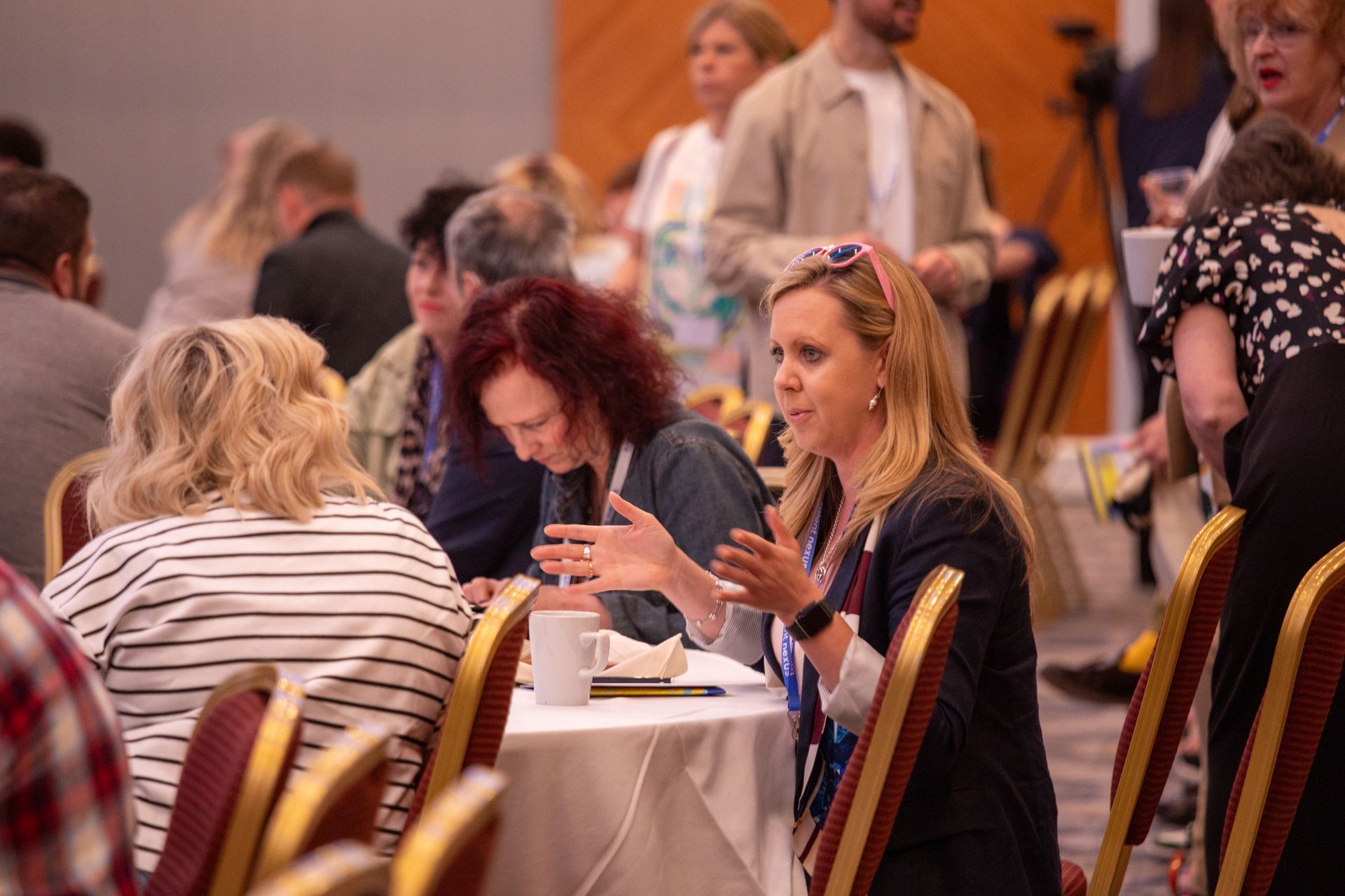A group of people are sitting at tables in a conference room.