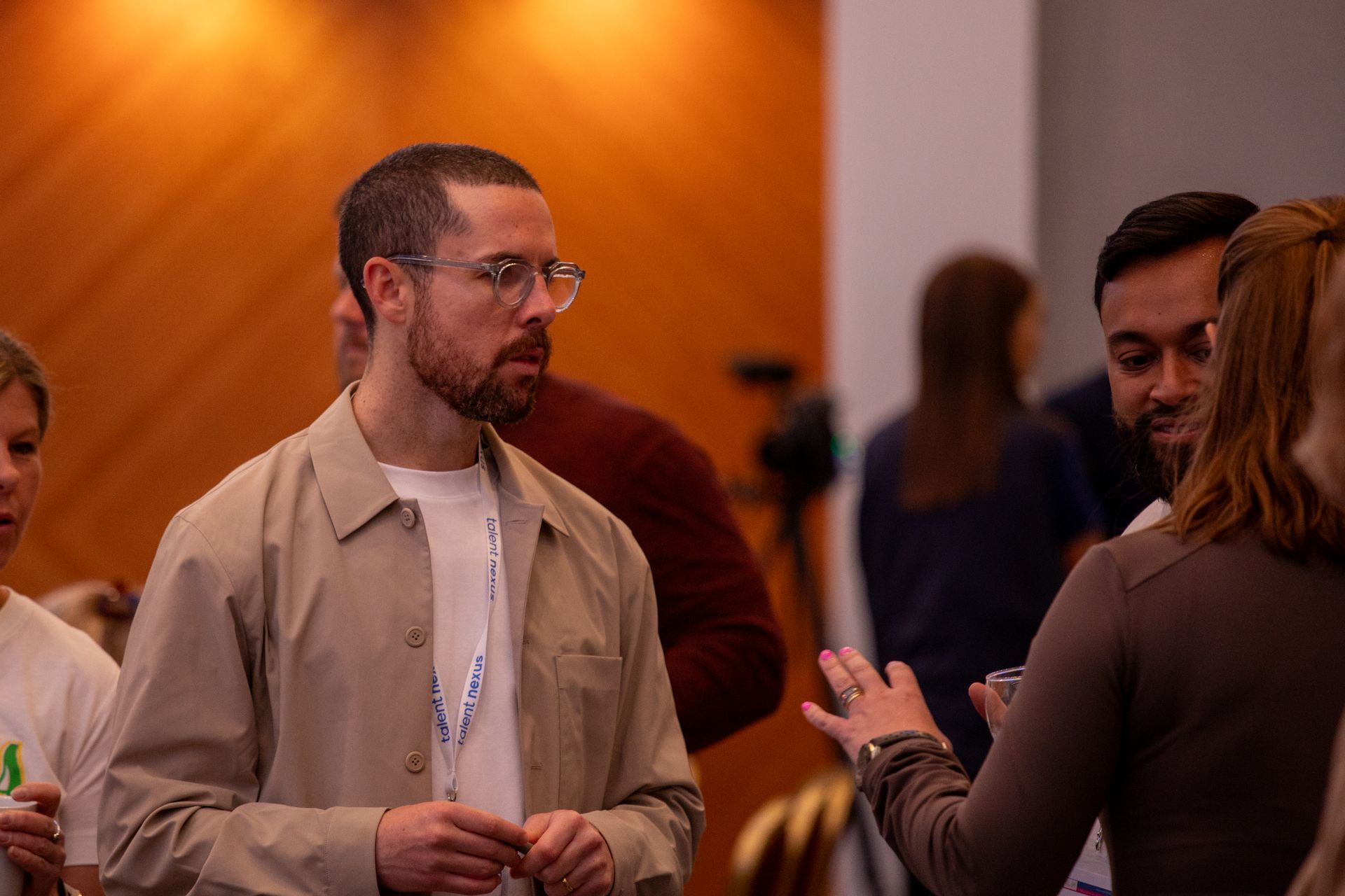 A man with glasses is talking to a group of people in a room.