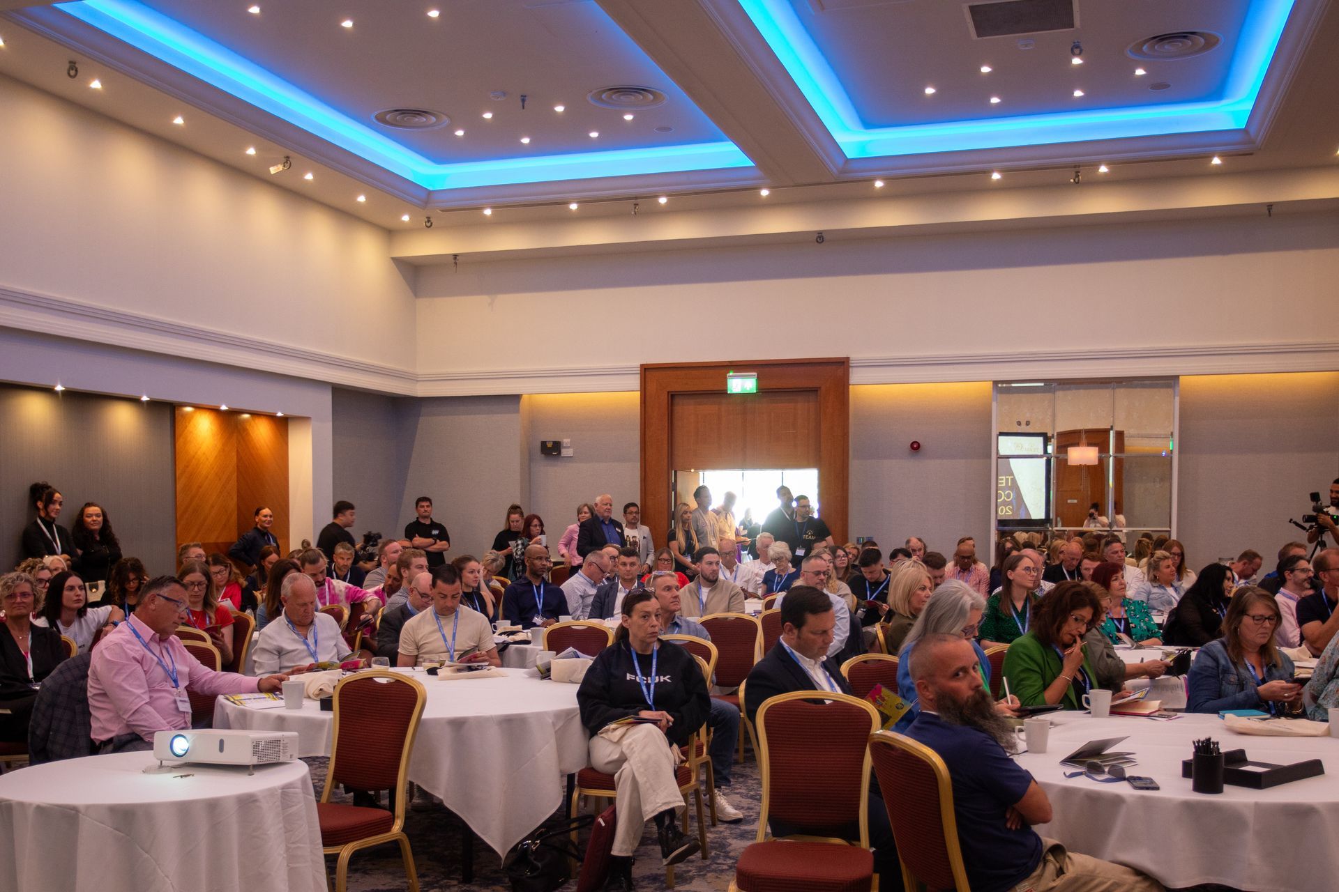 A large group of people are sitting at tables in a conference room.