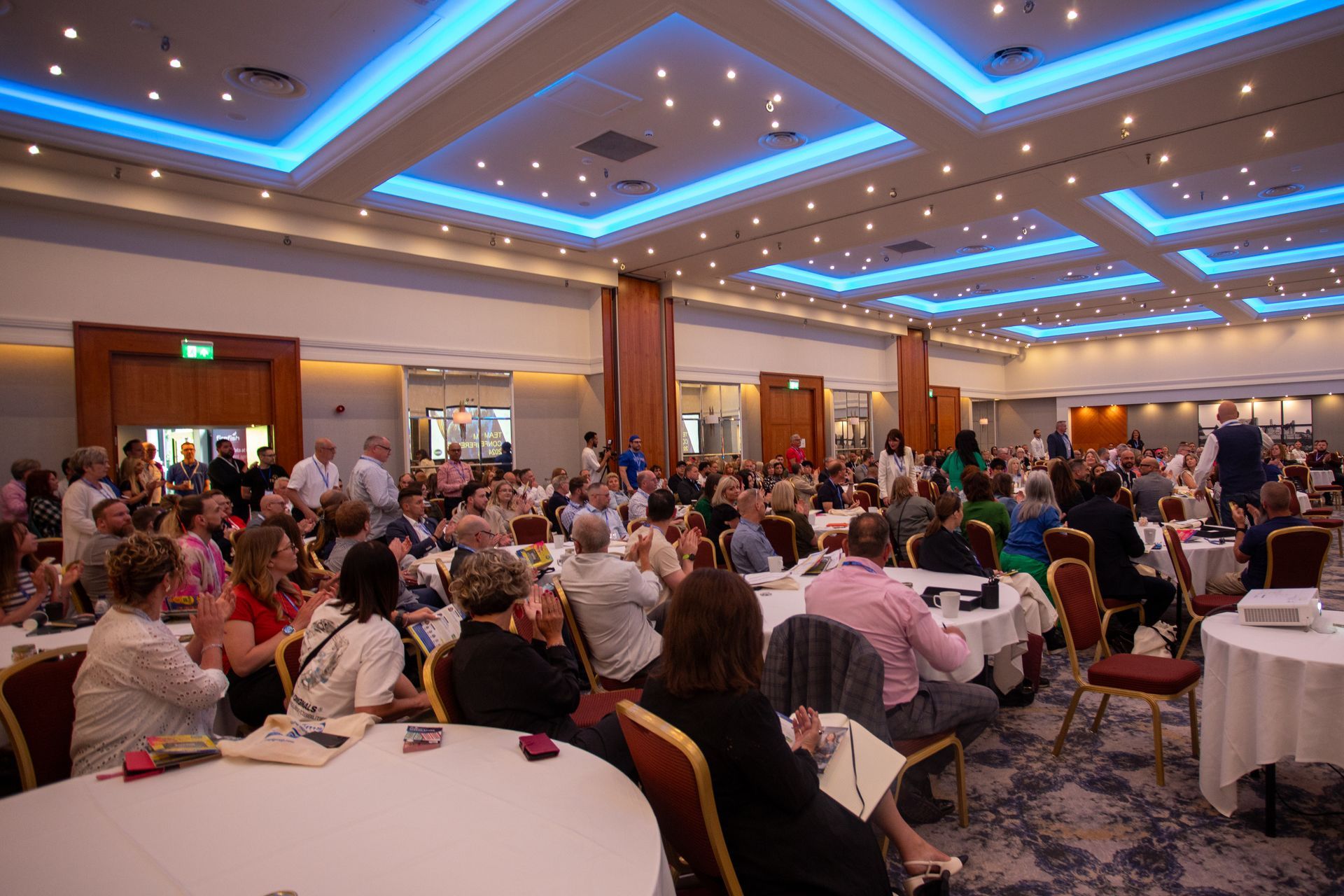 A large group of people are sitting at tables in a large room.