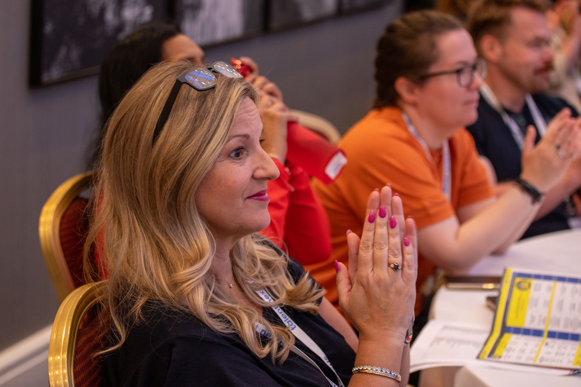 A group of people are sitting at a table clapping their hands.