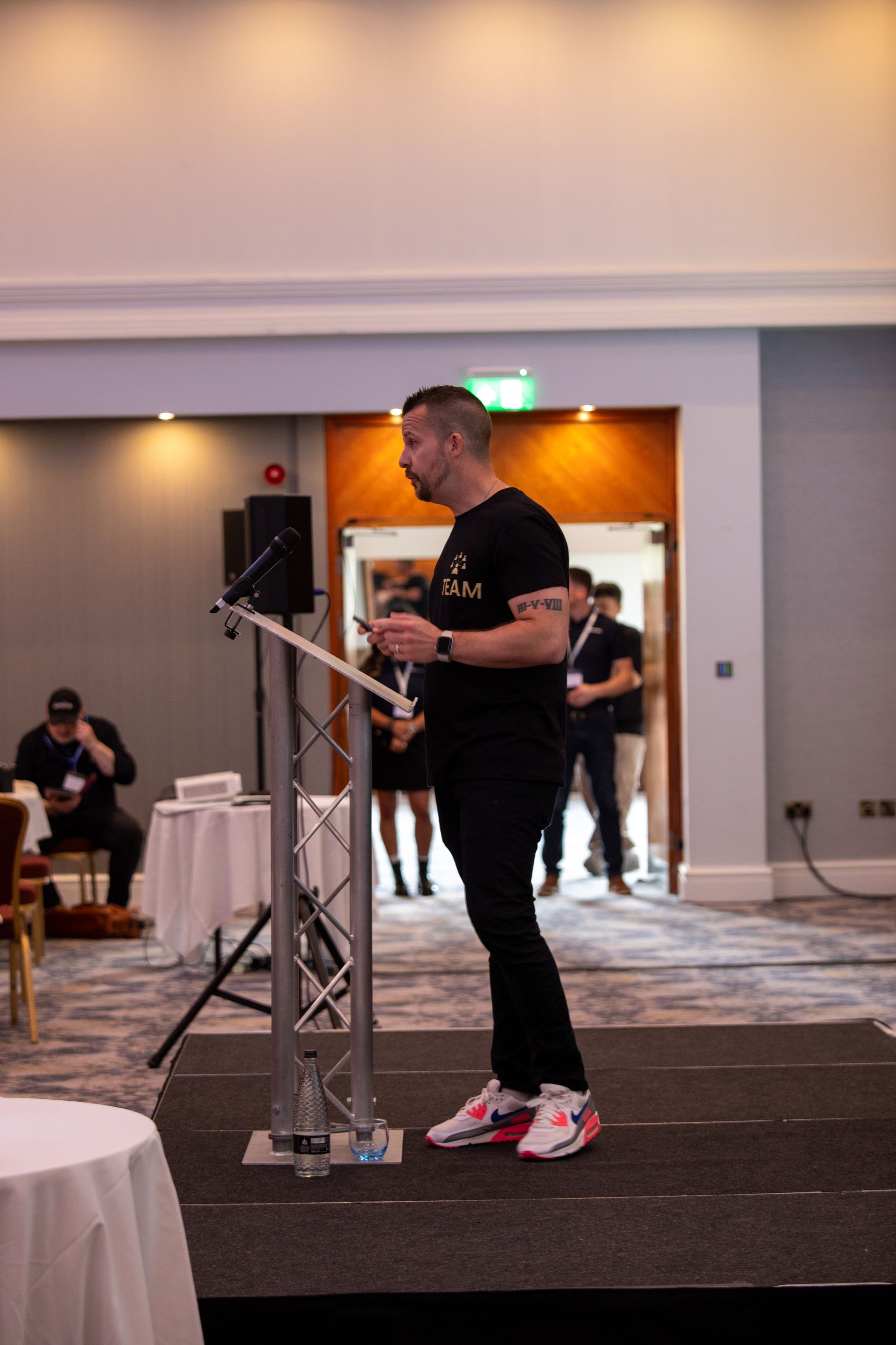 A man is standing at a podium giving a speech in a room.