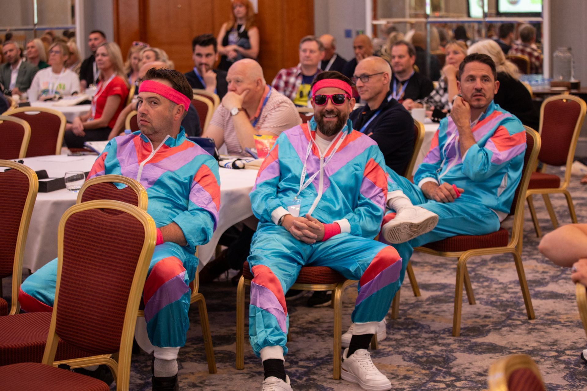 A group of men in colorful suits are sitting in chairs in a room.