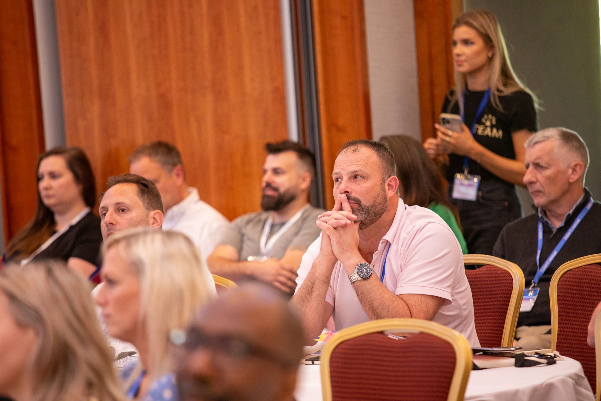A group of people are sitting at tables in a conference room.