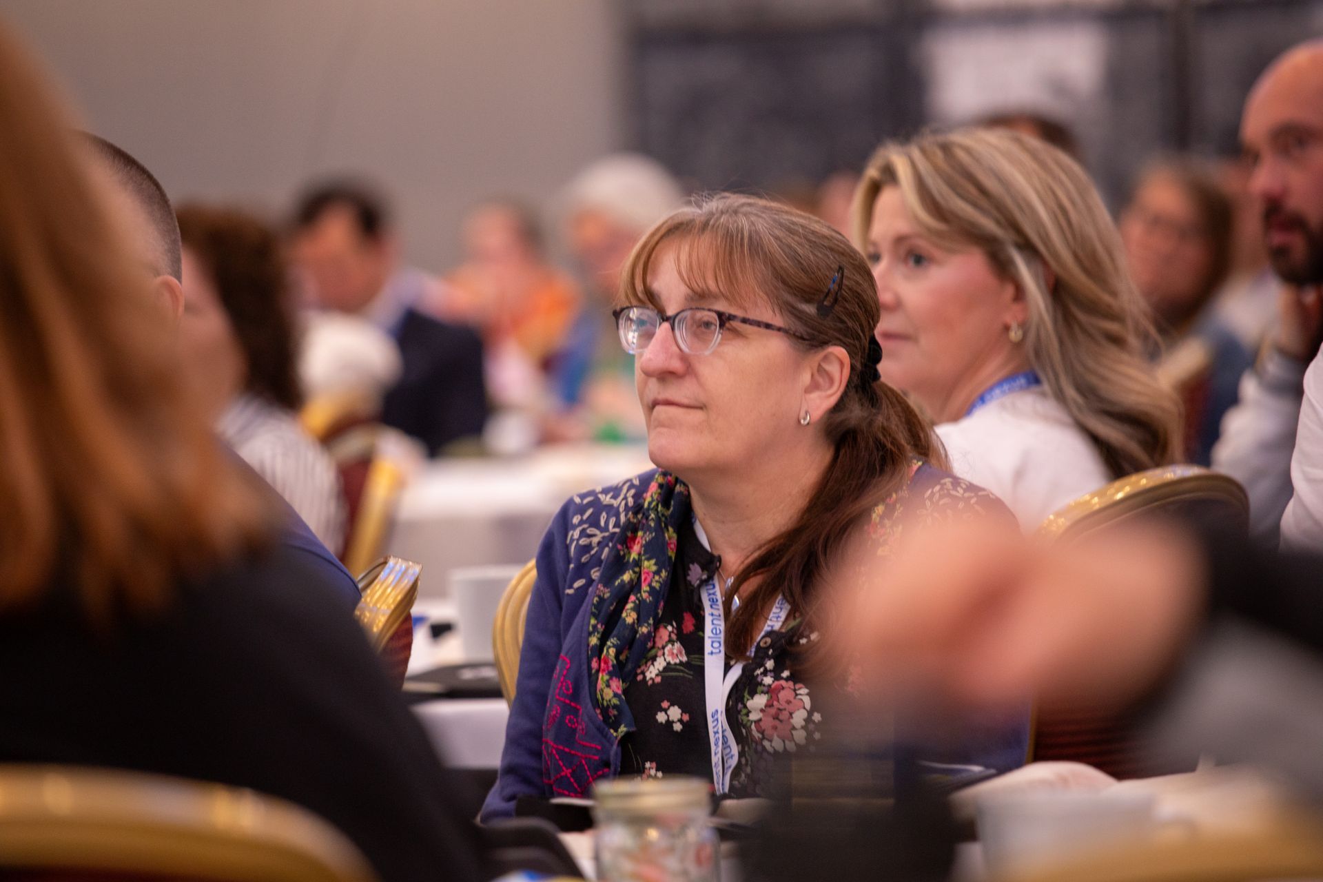 A group of people are sitting at tables in a conference room.