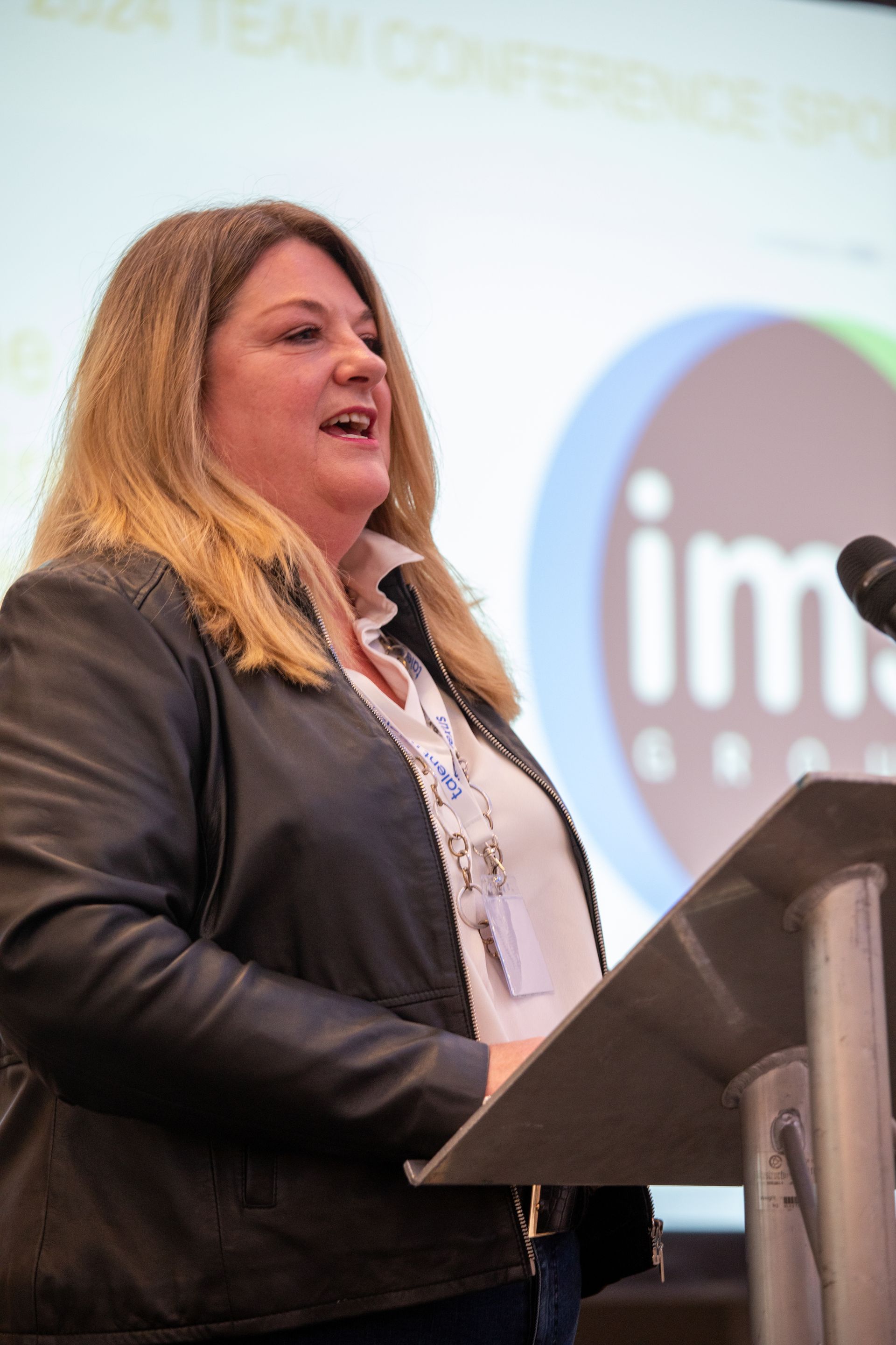 A woman is standing at a podium speaking into a microphone.