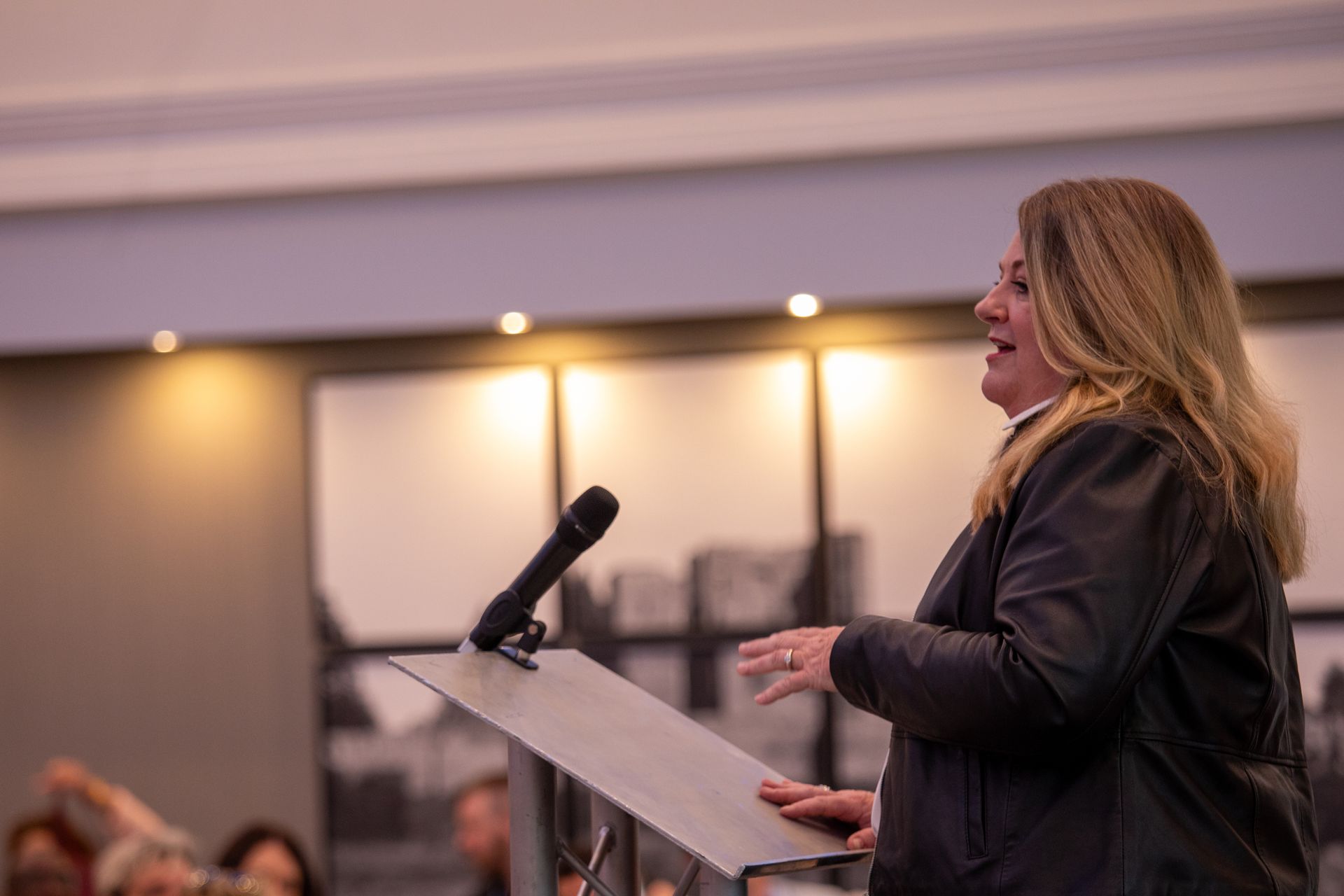 A woman is standing at a podium speaking into a microphone.
