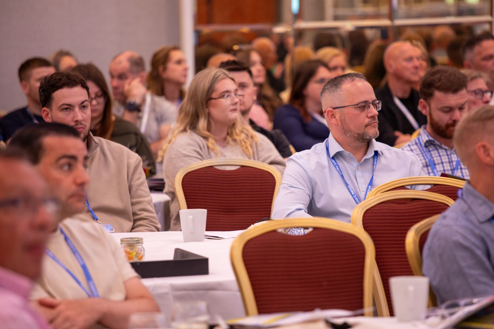 A group of people are sitting at tables in a conference room.