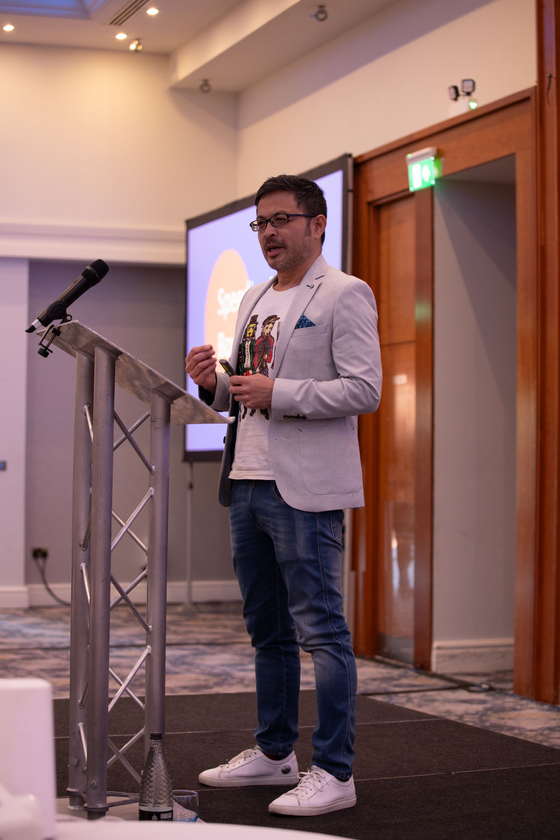 A man is standing at a podium holding a microphone.