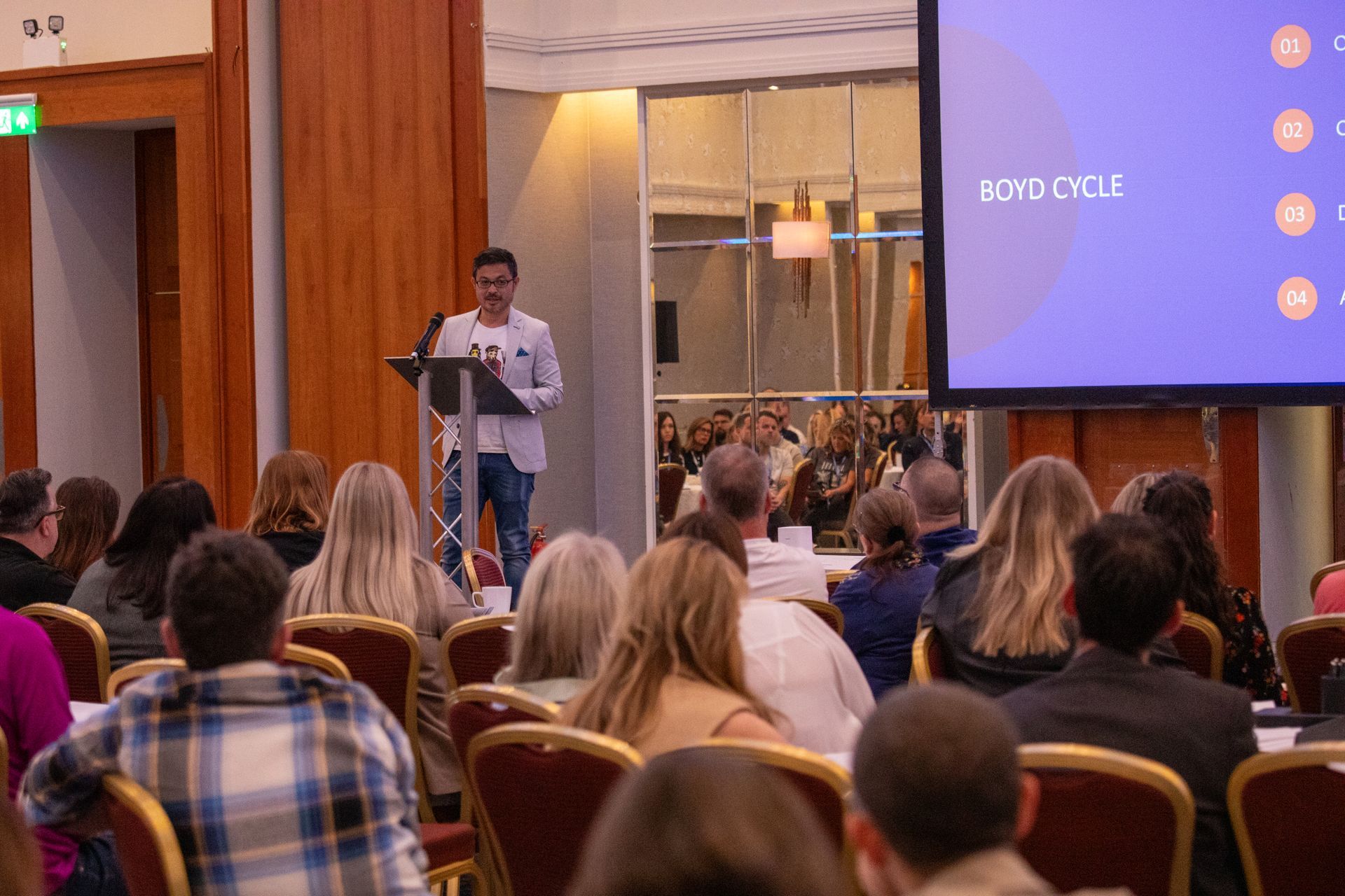 A man is standing at a podium giving a presentation to a group of people.