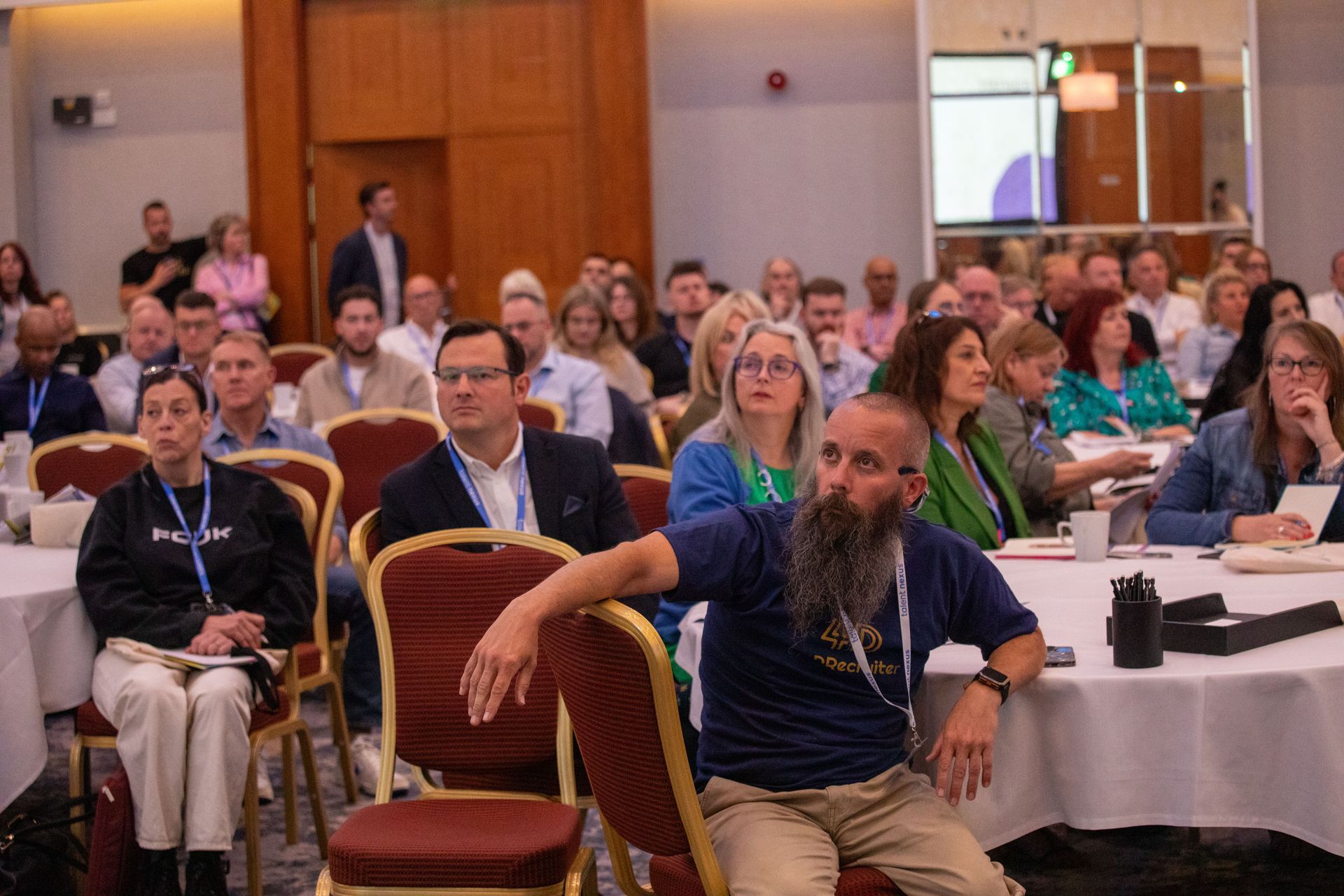 A large group of people are sitting at tables in a conference room.