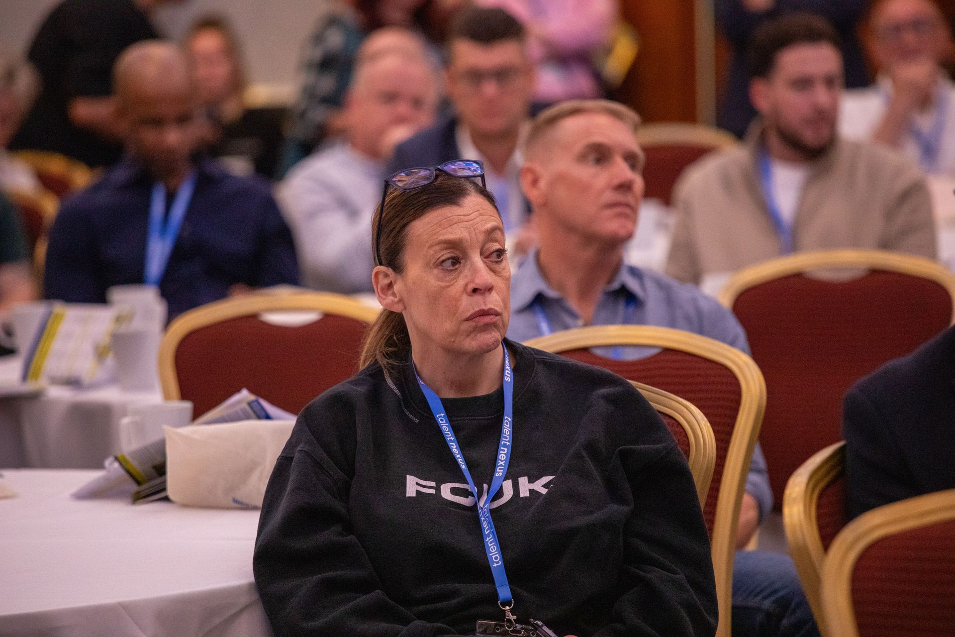 A woman is sitting in a crowd of people at a conference.