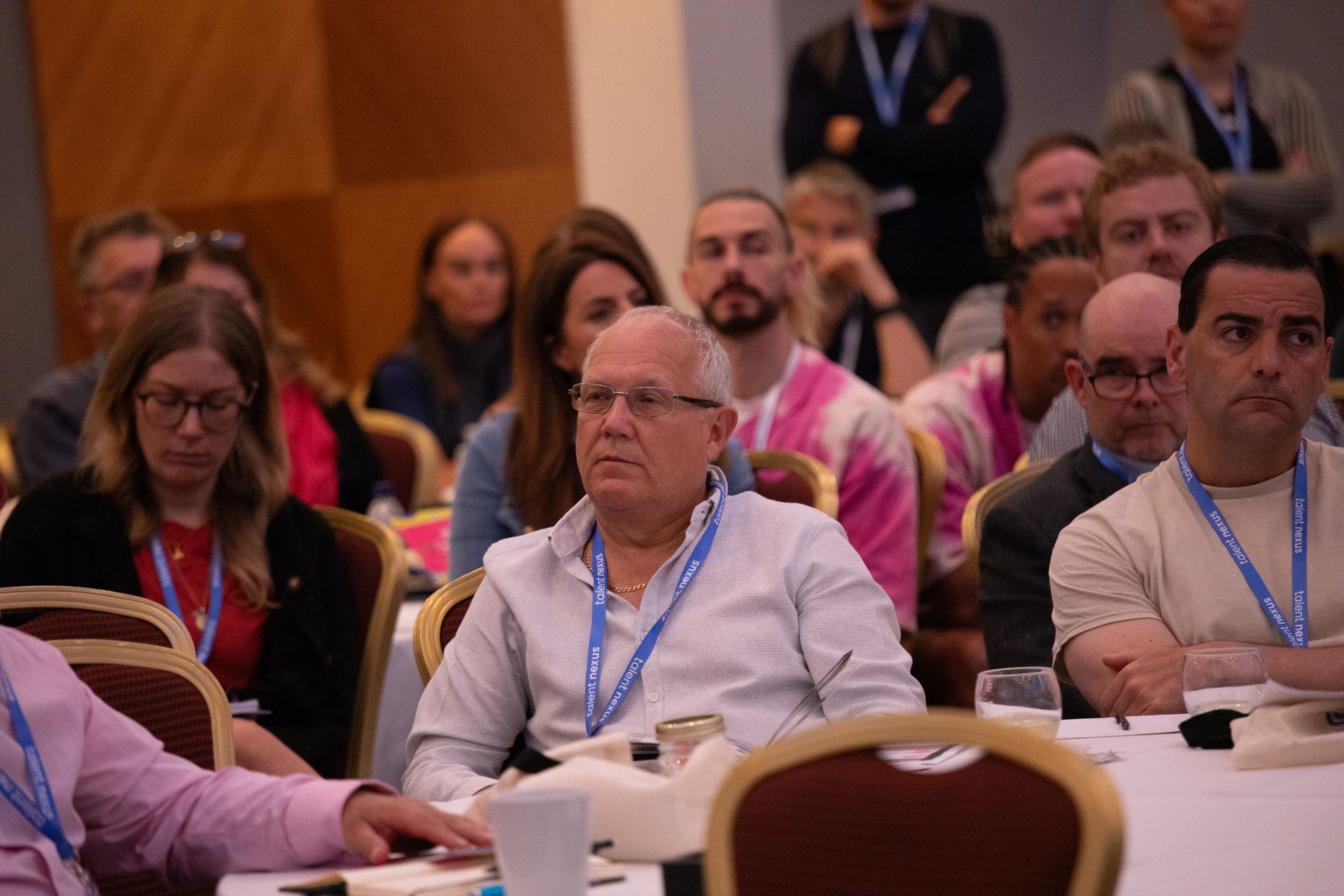A group of people are sitting at tables in a conference room.