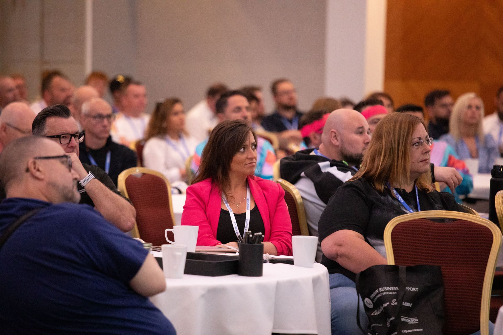 A group of people are sitting at tables in a conference room.