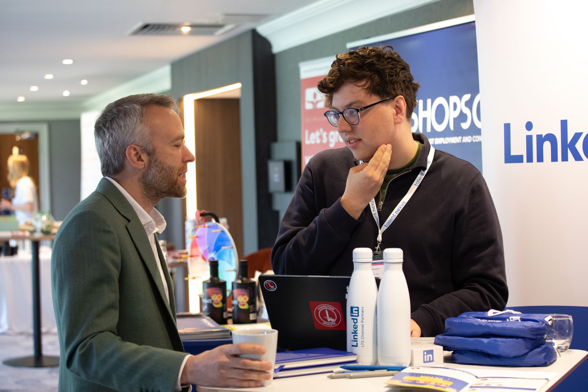 Two men are sitting at a table talking to each other.