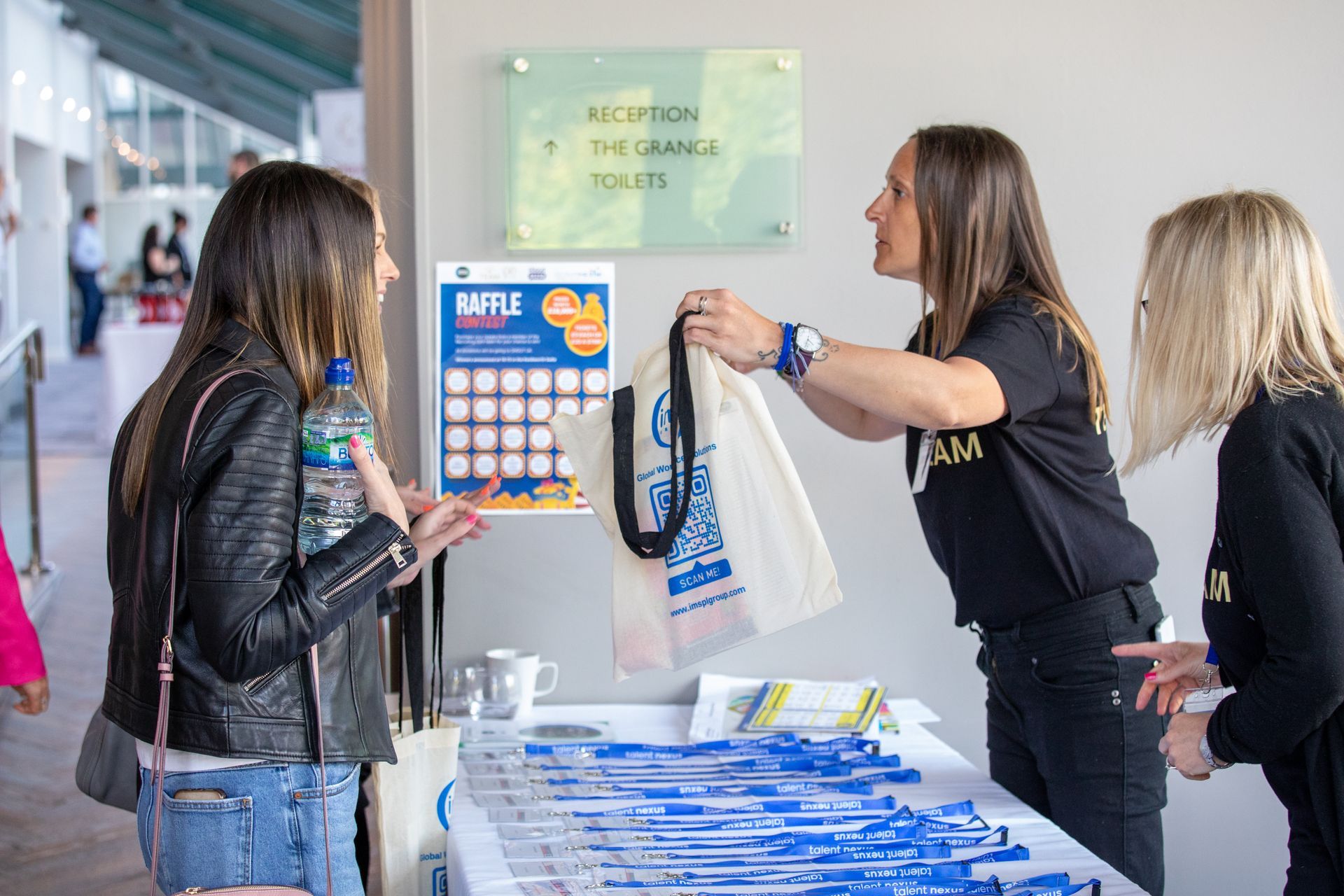A woman is giving a bag to a woman at a table.