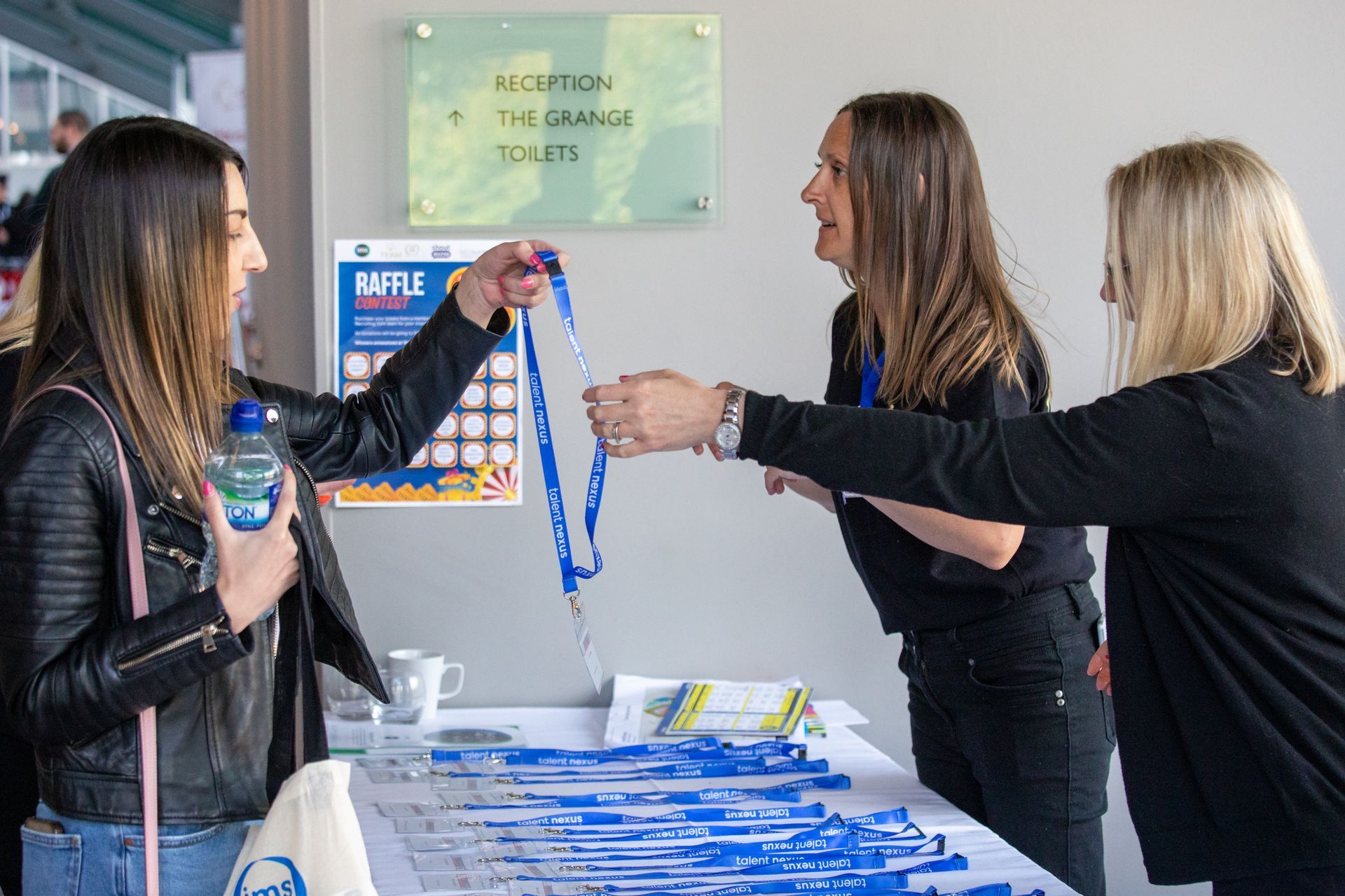 A group of women are standing around a table talking to each other.