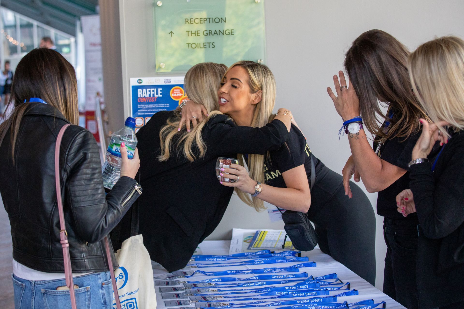 A group of women are hugging each other at a table.