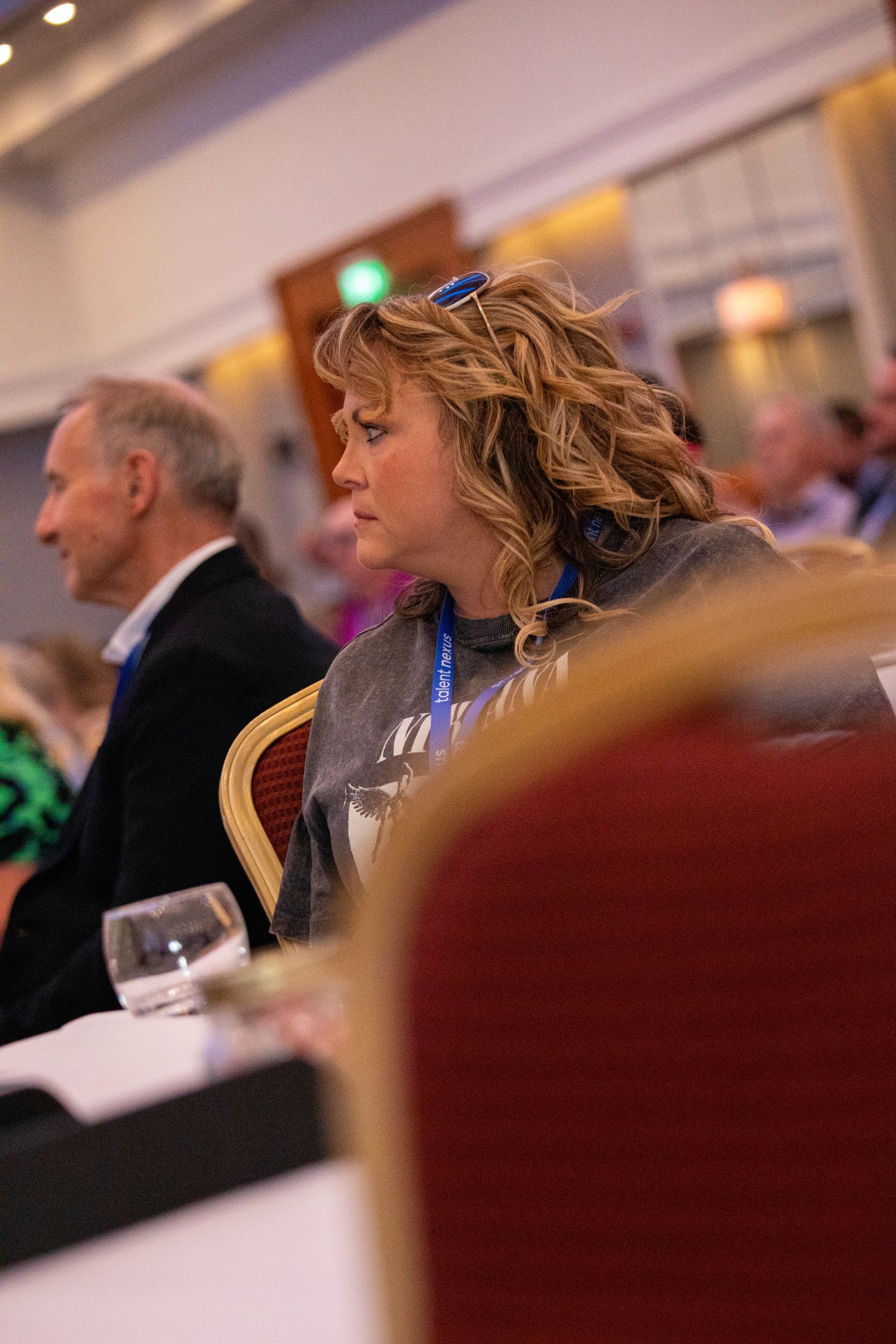 A woman is sitting at a table with a glass of wine.