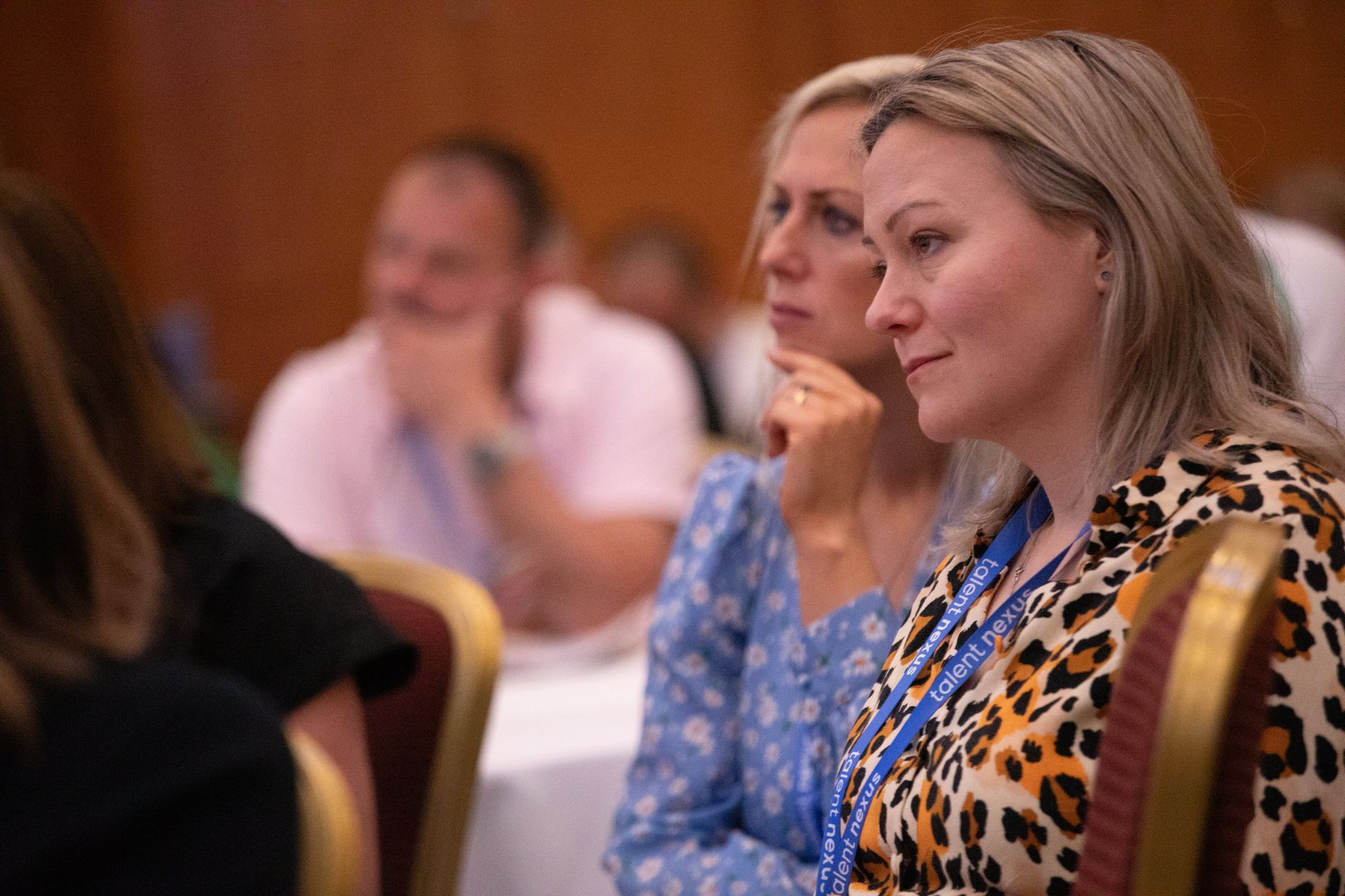 Two women are sitting in chairs at a conference.