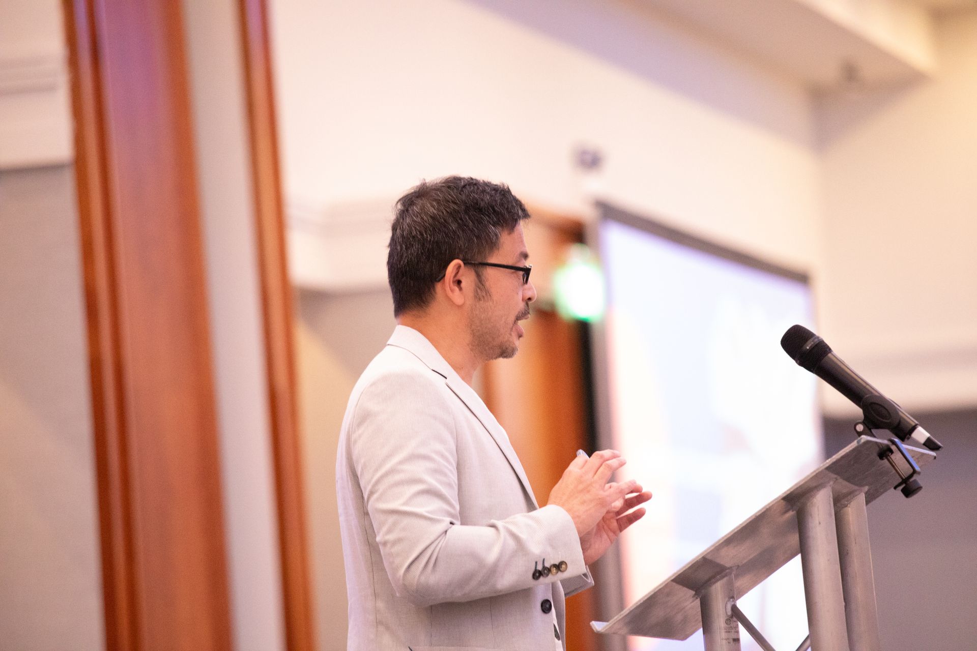 A man is standing at a podium speaking into a microphone.