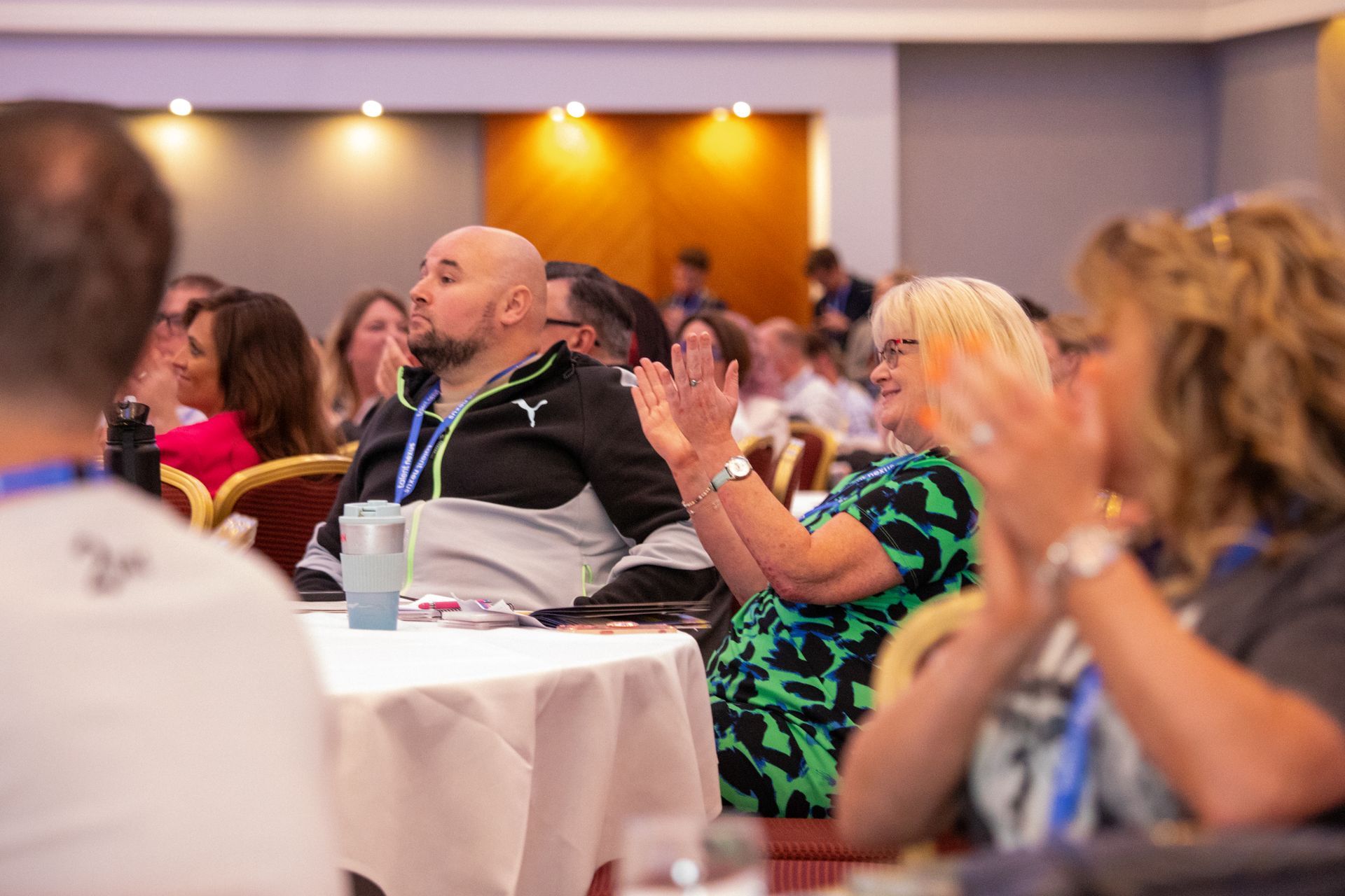 A group of people are sitting at tables in a room applauding.