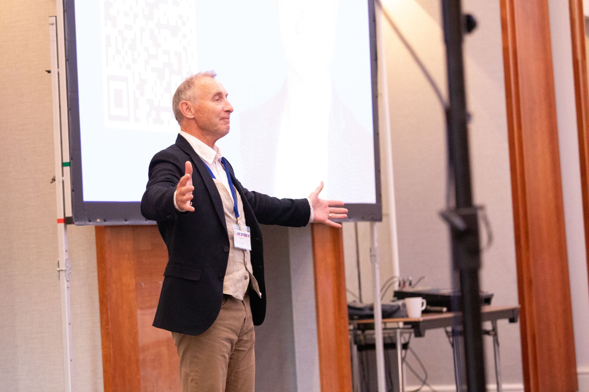 A man in a suit is giving a presentation in front of a large screen.