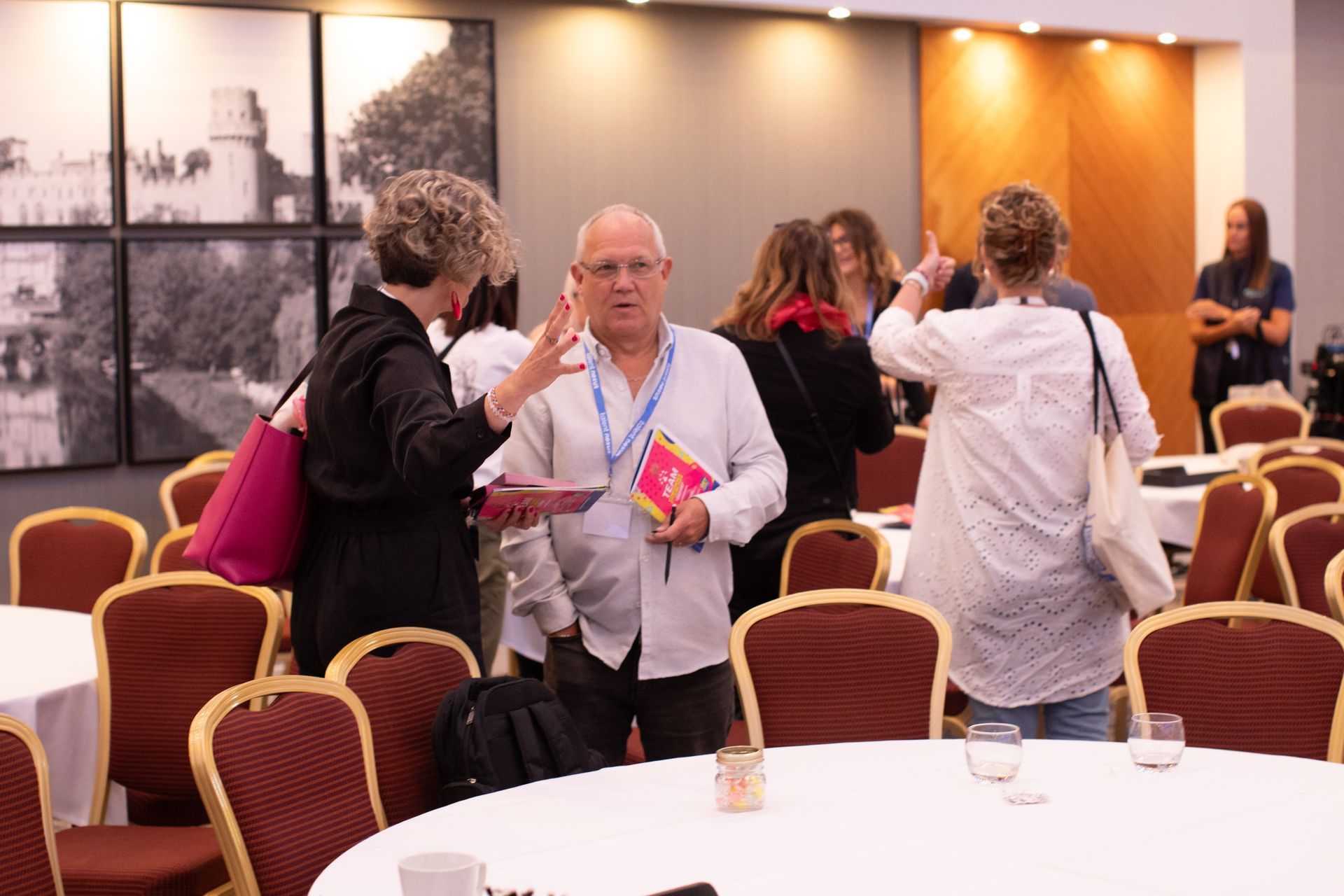 A group of people are standing around tables in a room.