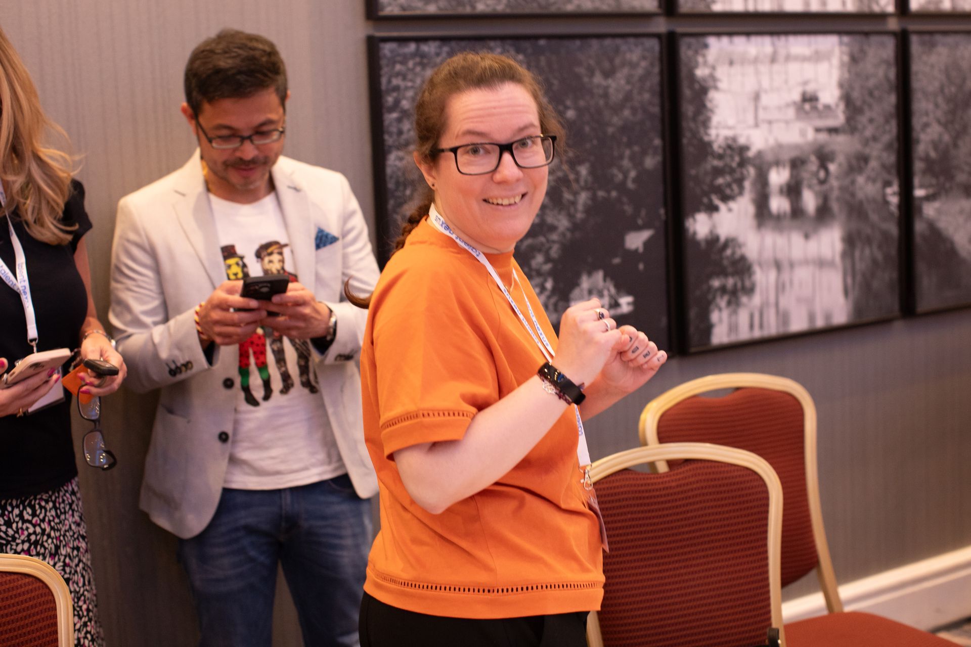A woman in an orange shirt is standing next to a man in a suit.