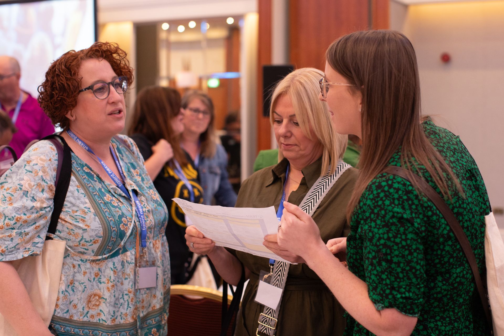 A group of women are standing next to each other and talking at a conference.