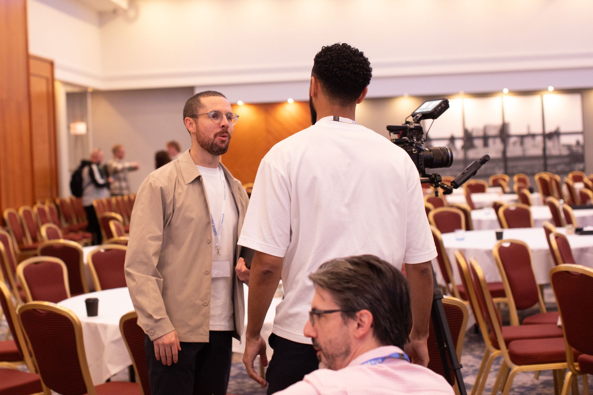 A group of men are standing in a room talking to each other.