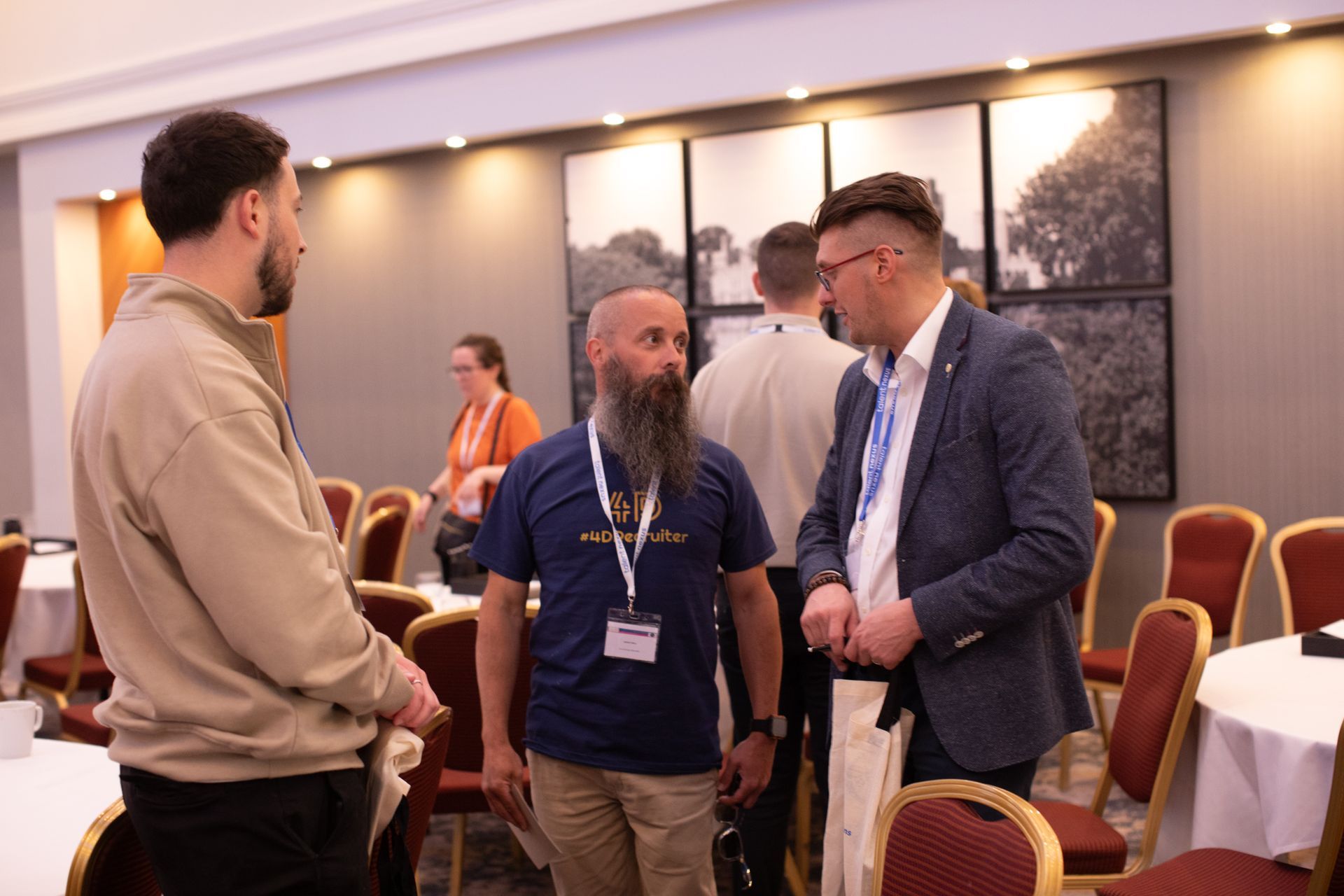 A group of men are standing in a room talking to each other.