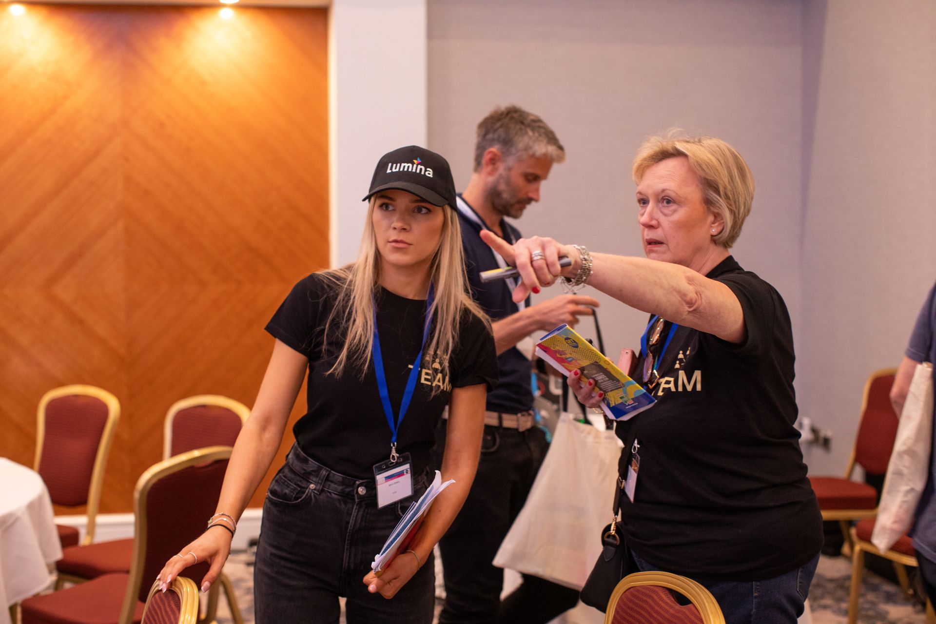 A group of people are standing in a room talking to each other.