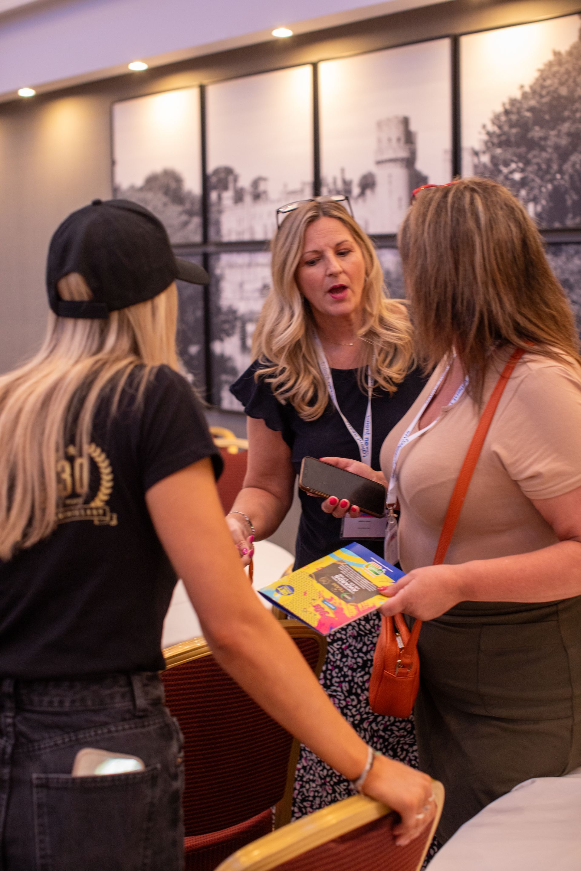 A group of women are standing around a table talking to each other.