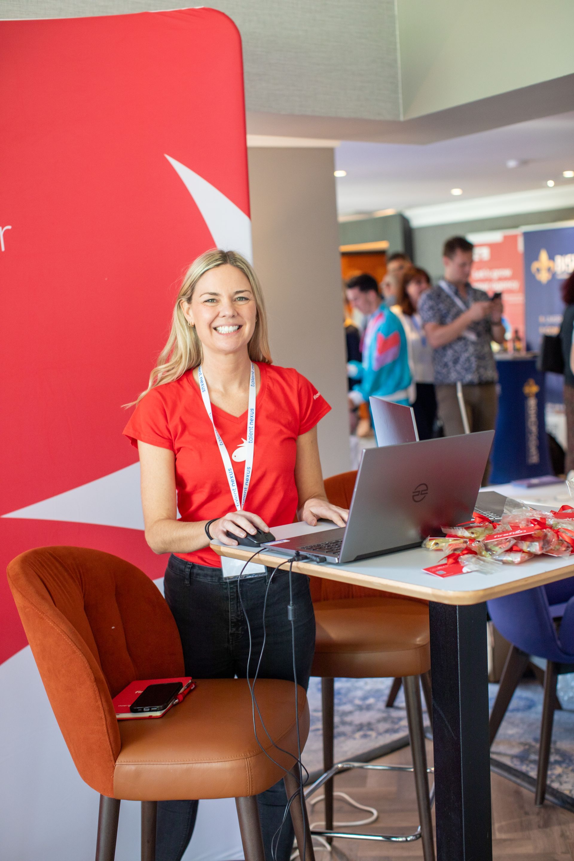 A woman is standing at a table with a laptop on it.