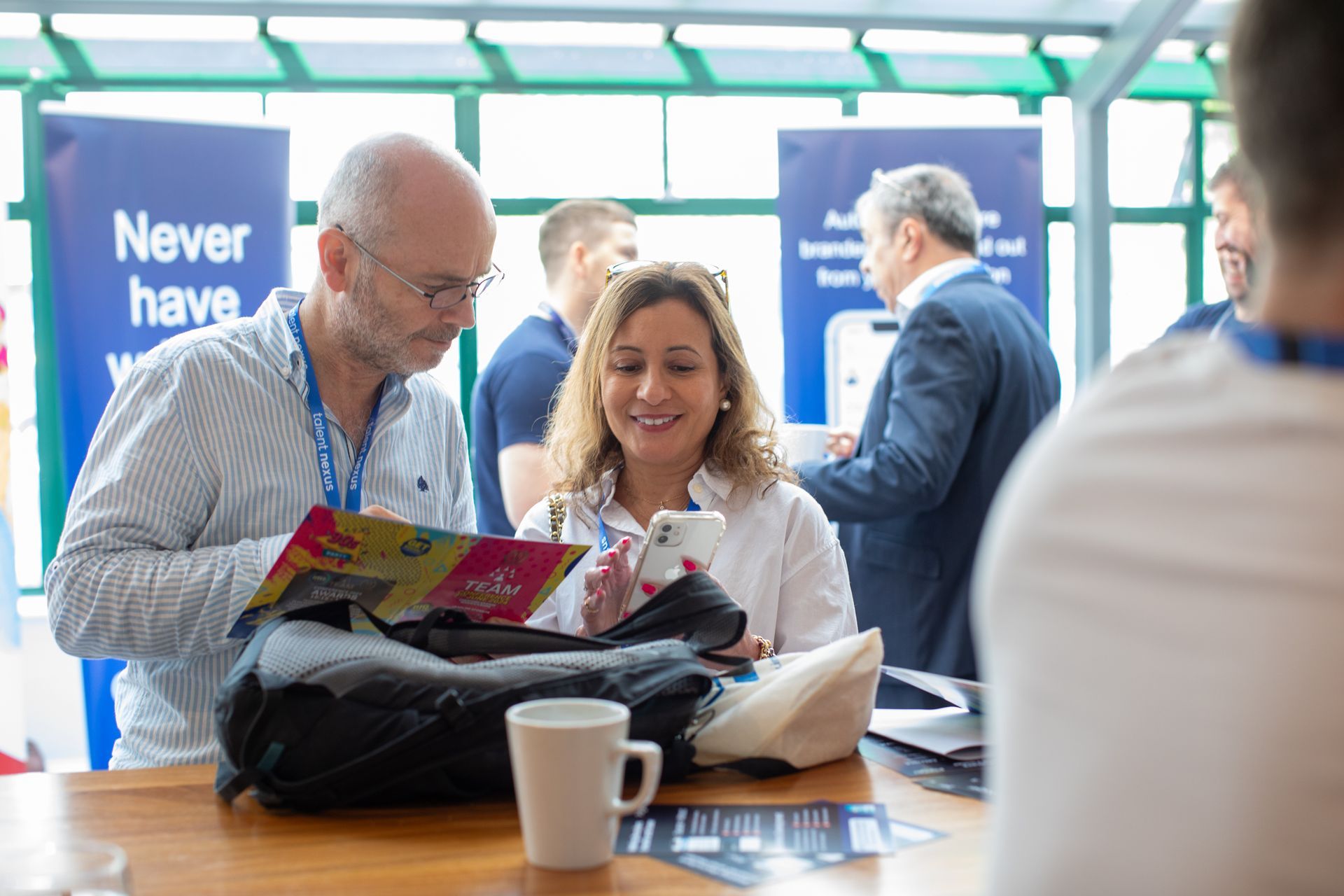 A man and a woman are sitting at a table looking at a book.