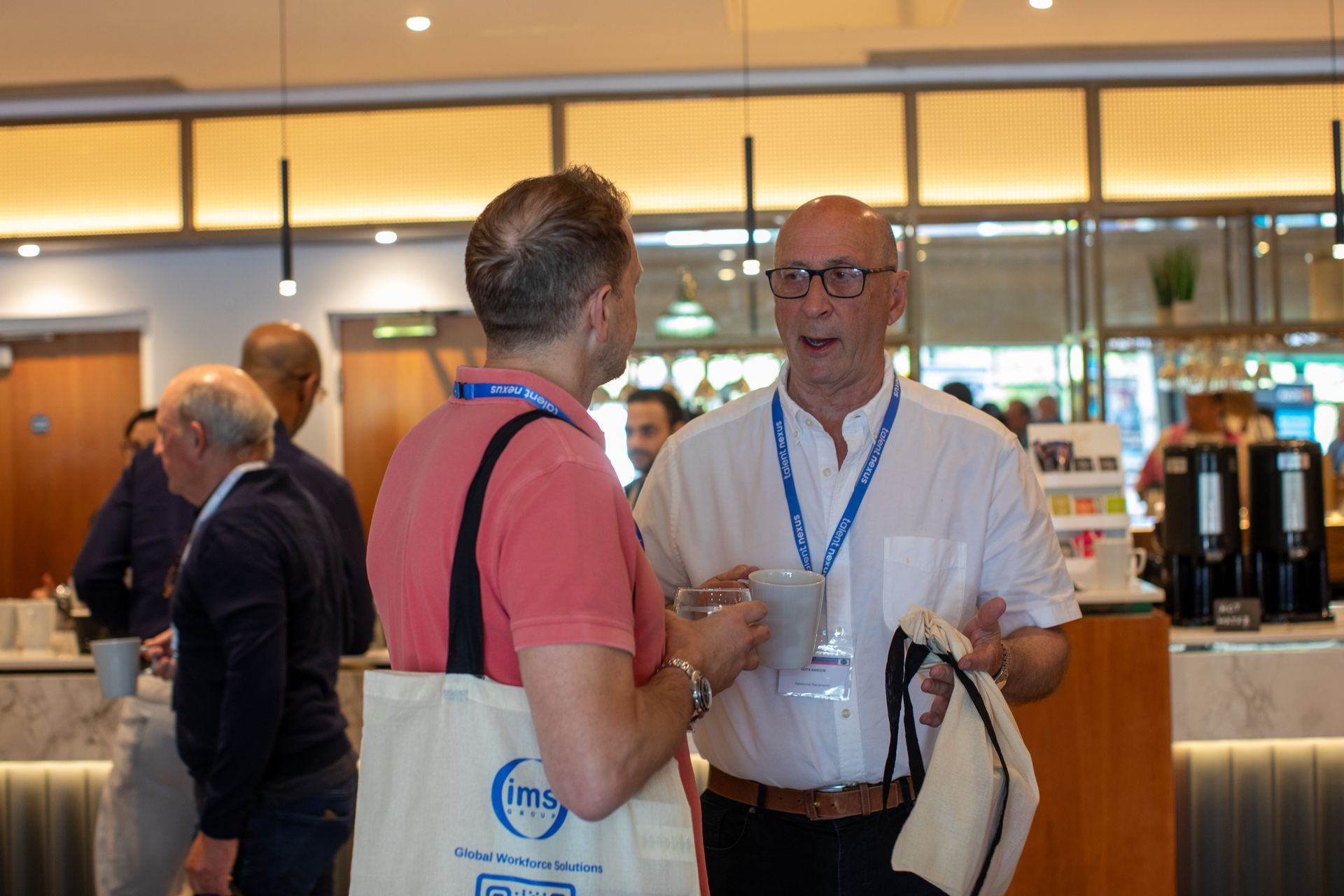 A group of men are standing in a room talking to each other.
