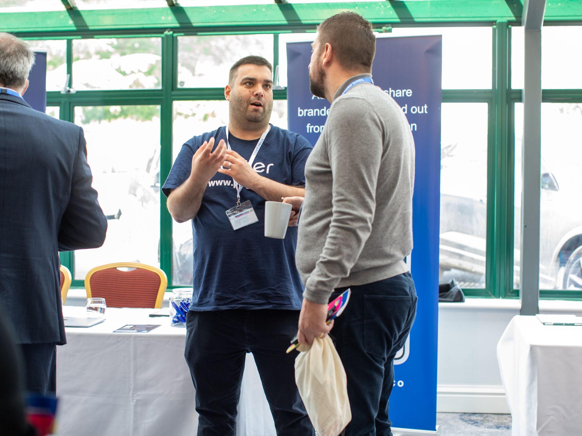 A group of men are standing in a room talking to each other.