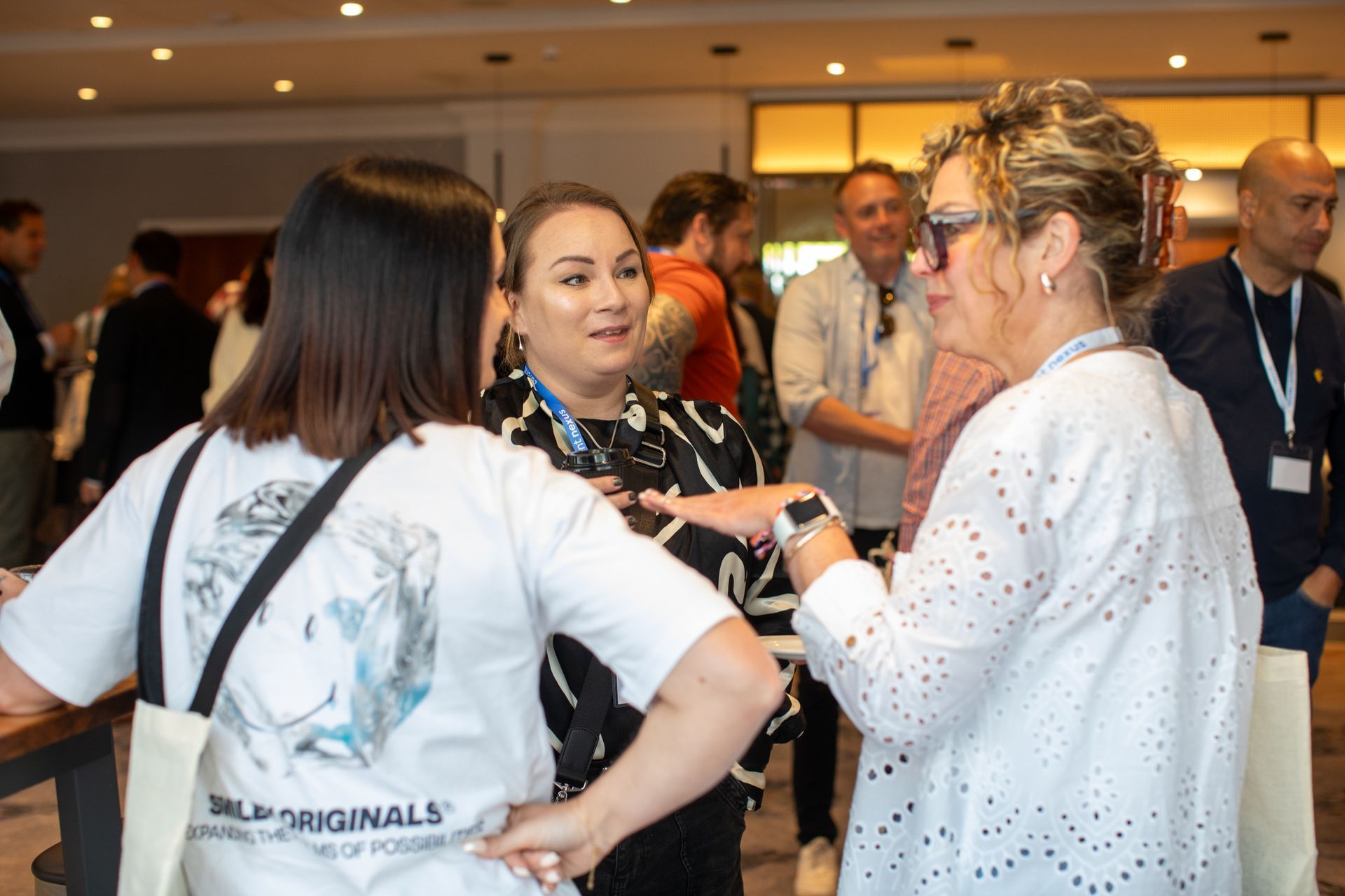 A group of people are standing in a room talking to each other.