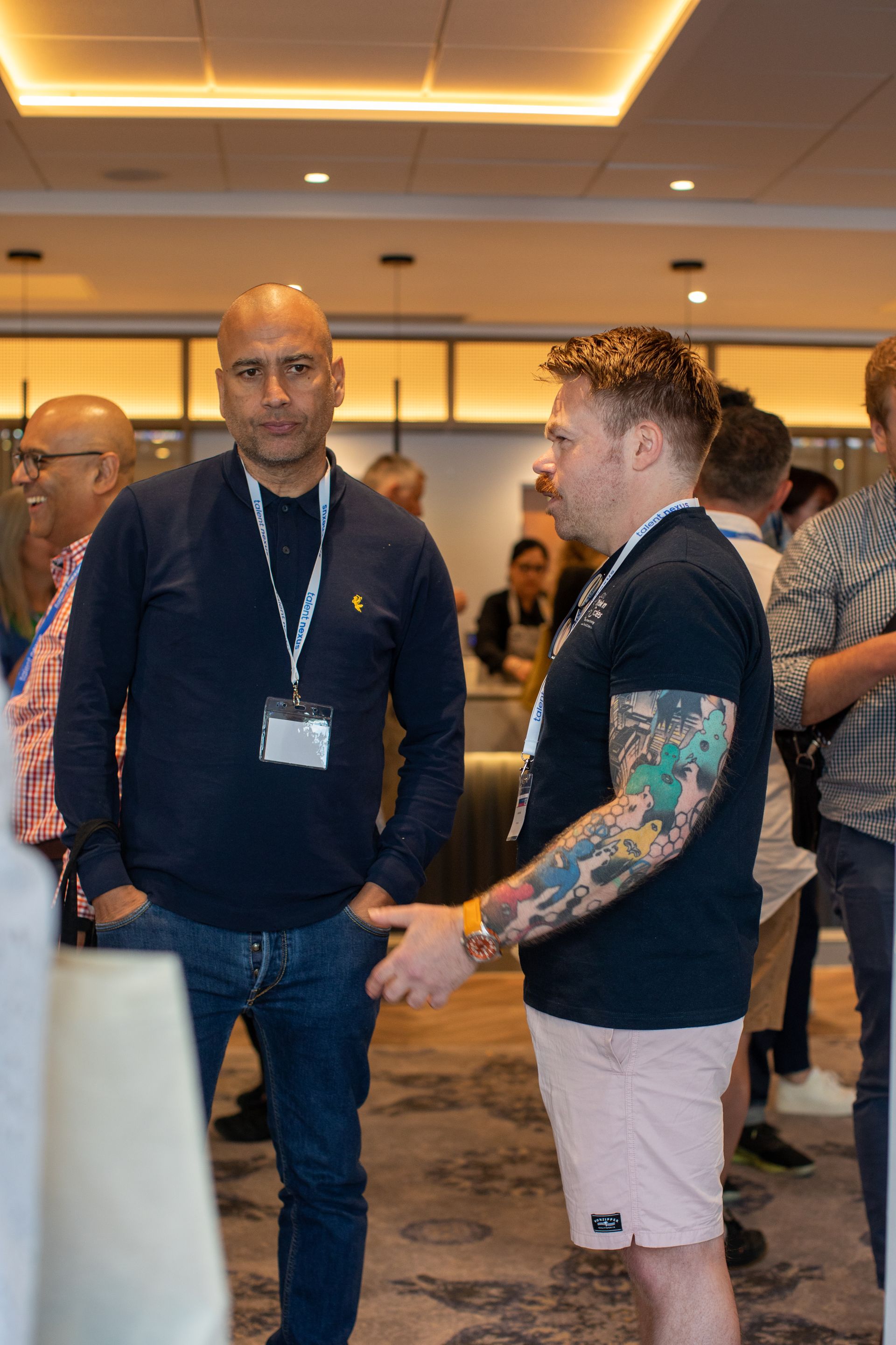 A group of men are standing in a room talking to each other.